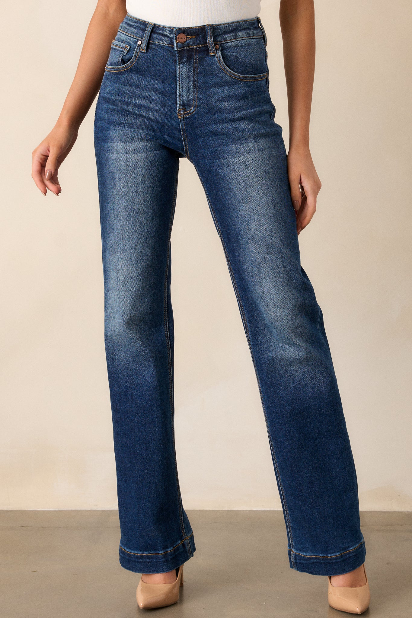 Front angled view of dark wash jeans featuring a high waisted design, functional belt loops, faded thigh and knee areas, and a straight leg fit