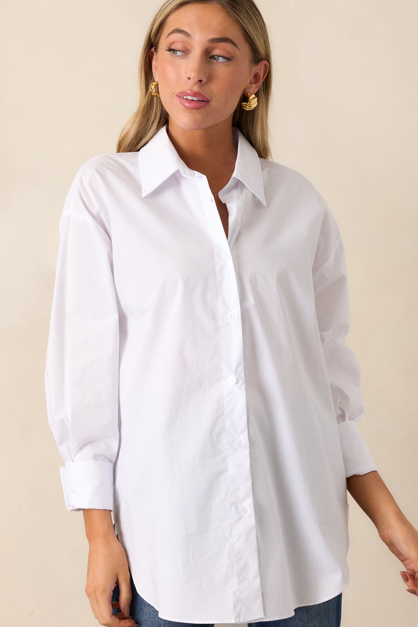 Full view of the white top featuring a collared neckline, button front, and voluminous balloon sleeves with buttoned cuffs.