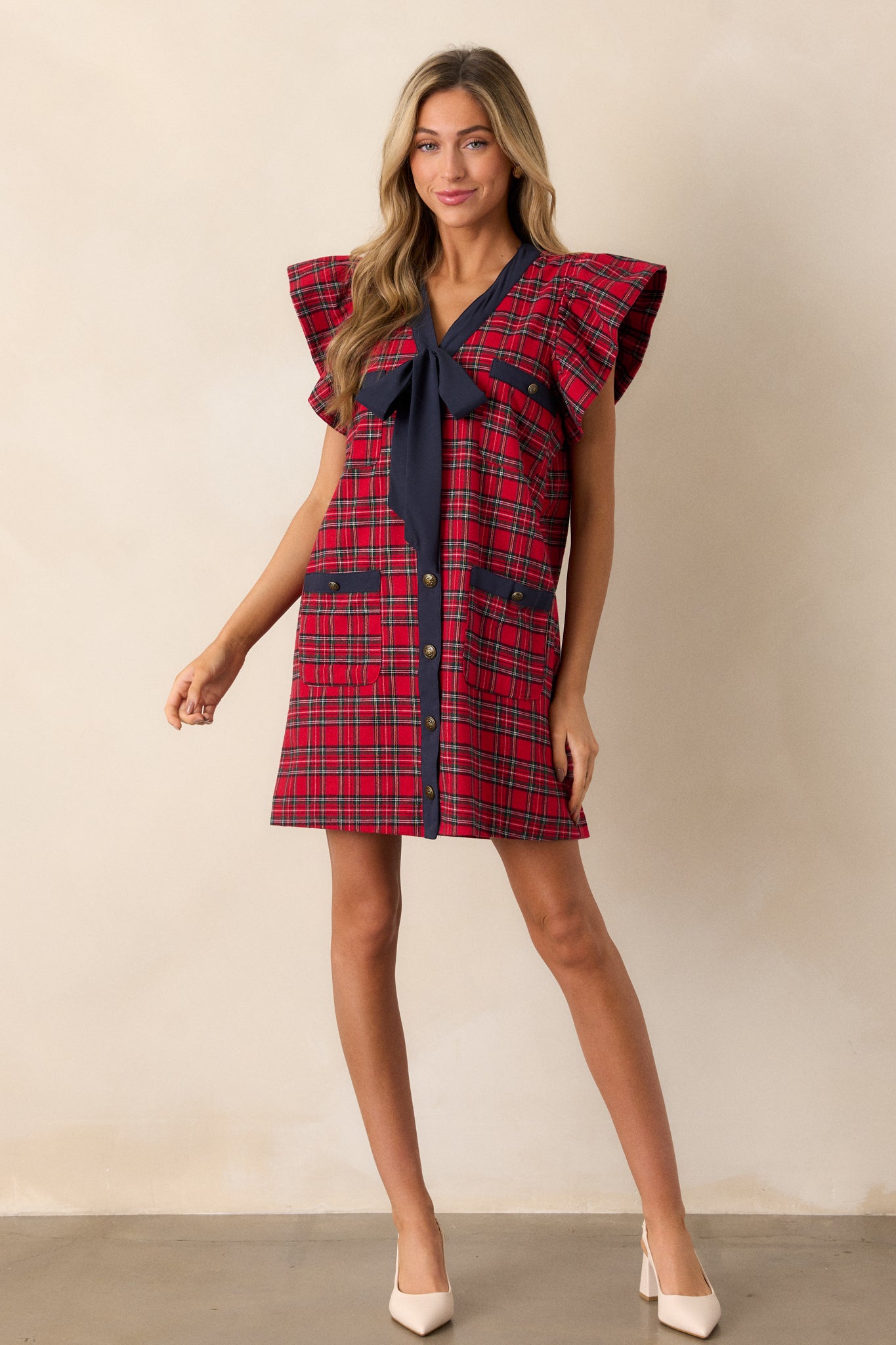 A plaid mini dress with functional gold buttons, flutter sleeves, and two sets of functional pockets, showcasing its relaxed fit.