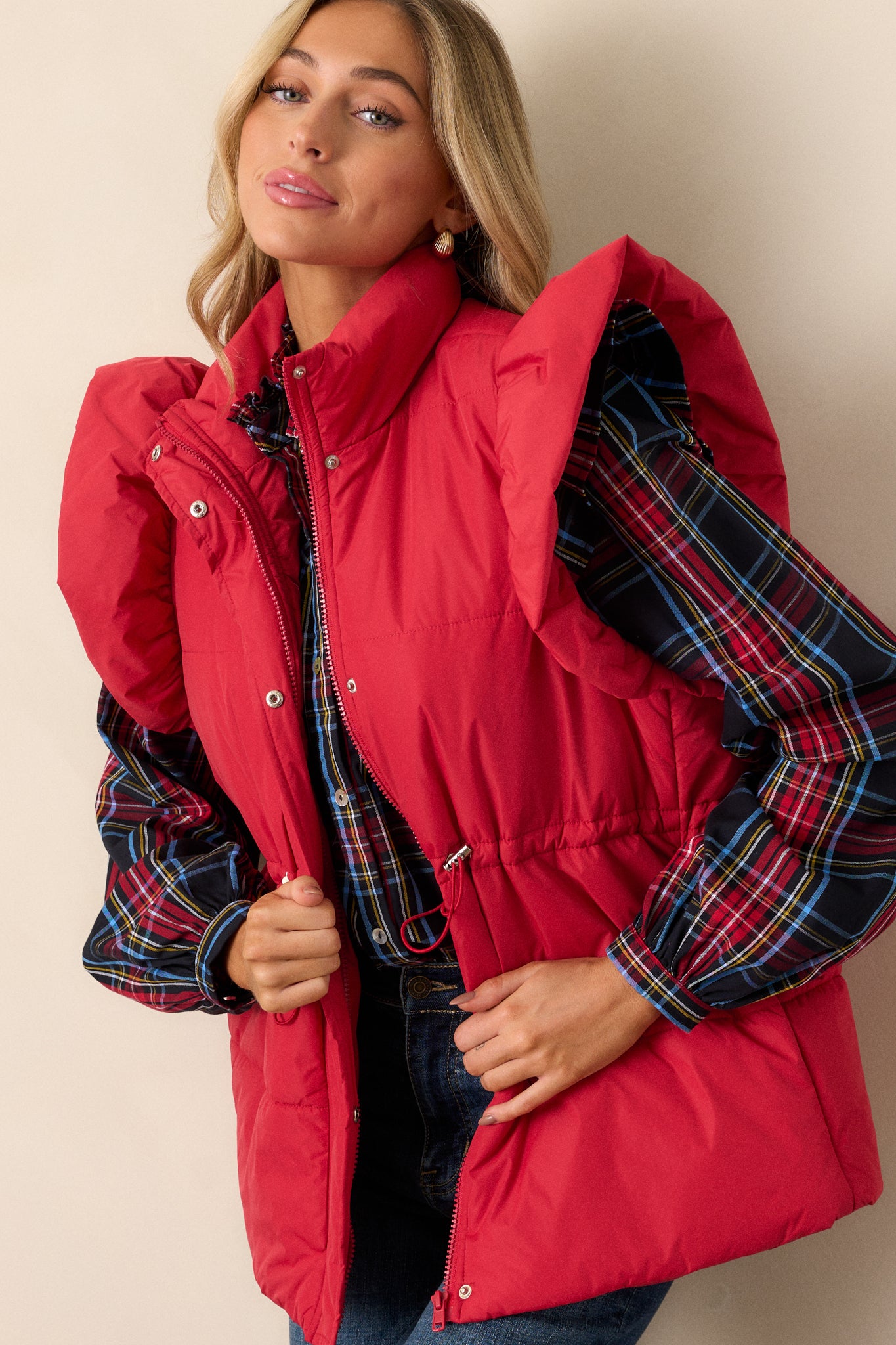 Close-up of the string cinch waist with silver hardware on the red puffer vest, highlighting the detailed tailoring and fit.