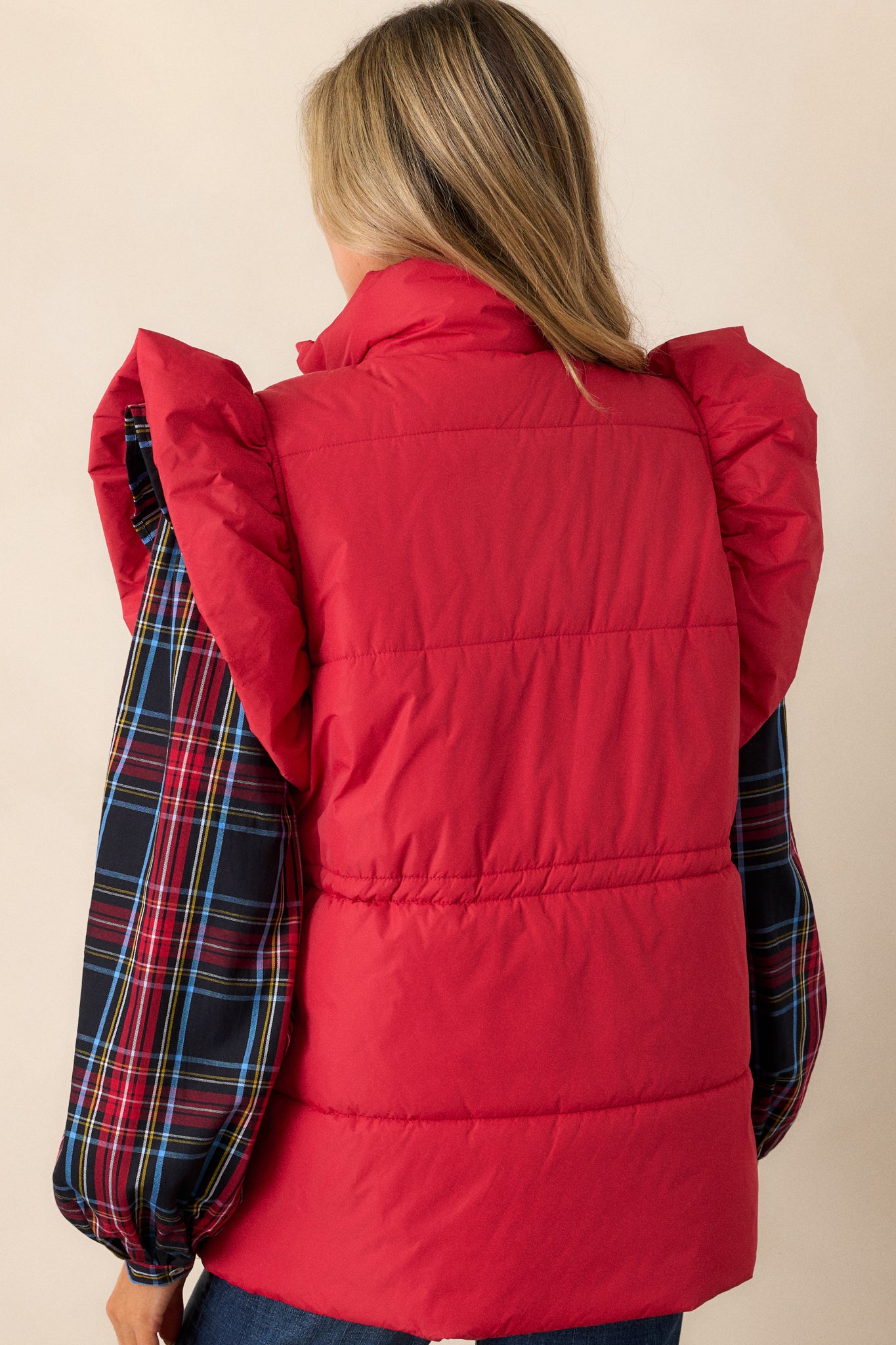 The back of the red puffer vest, featuring puffer line detailing and a cinched waist for a fitted, structured look.