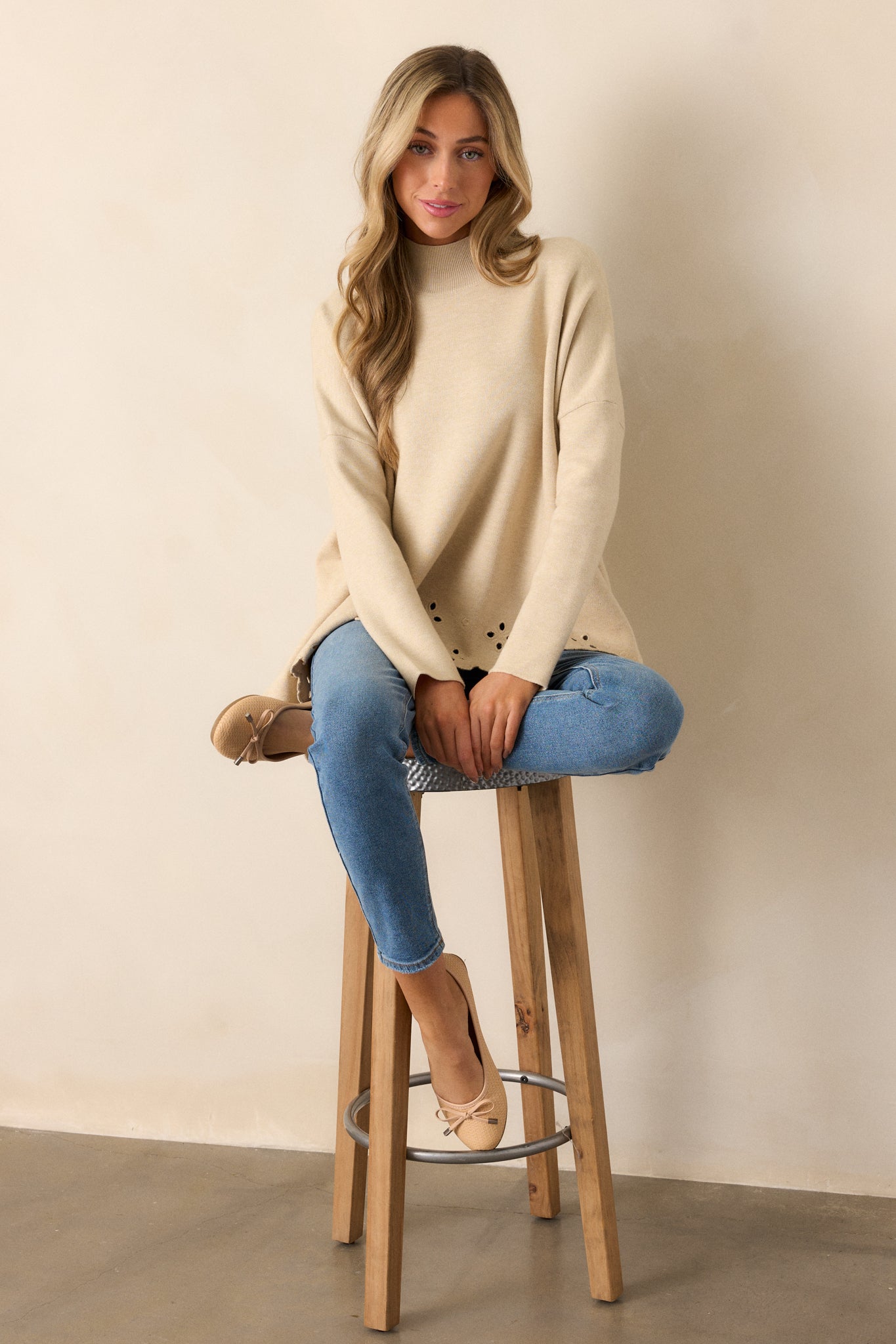 A front-facing view of the sweater, highlighting the high ribbed neckline, relaxed boxy fit, and scalloped eyelet hem.