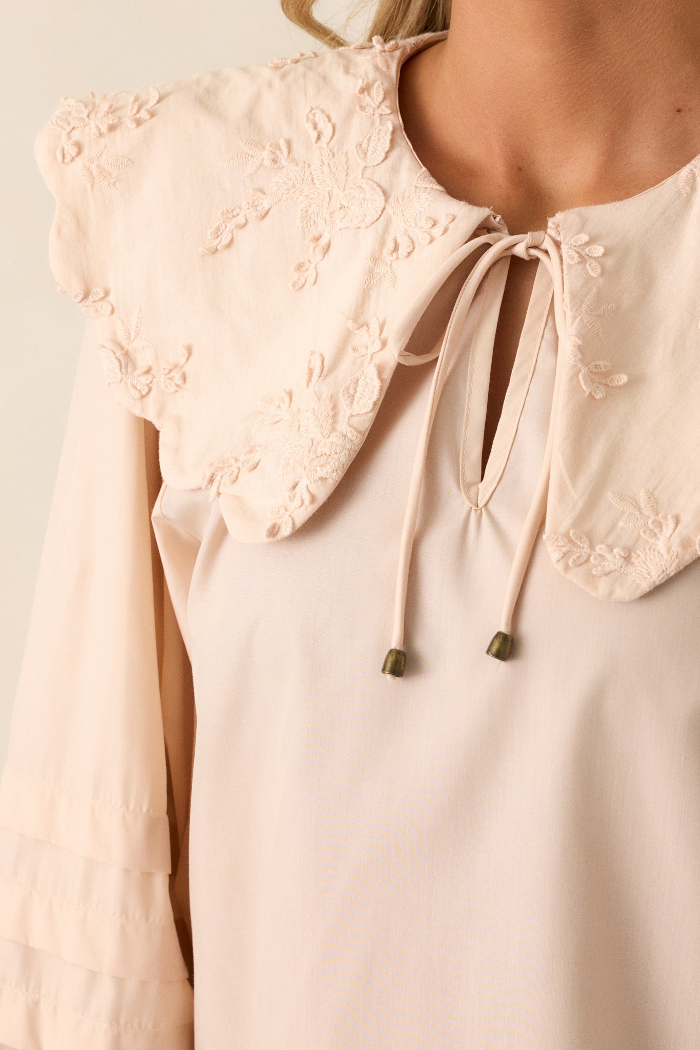 Extreme close-up of the scalloped collar, focusing on the intricate floral embroidery and the fine stitch detailing.