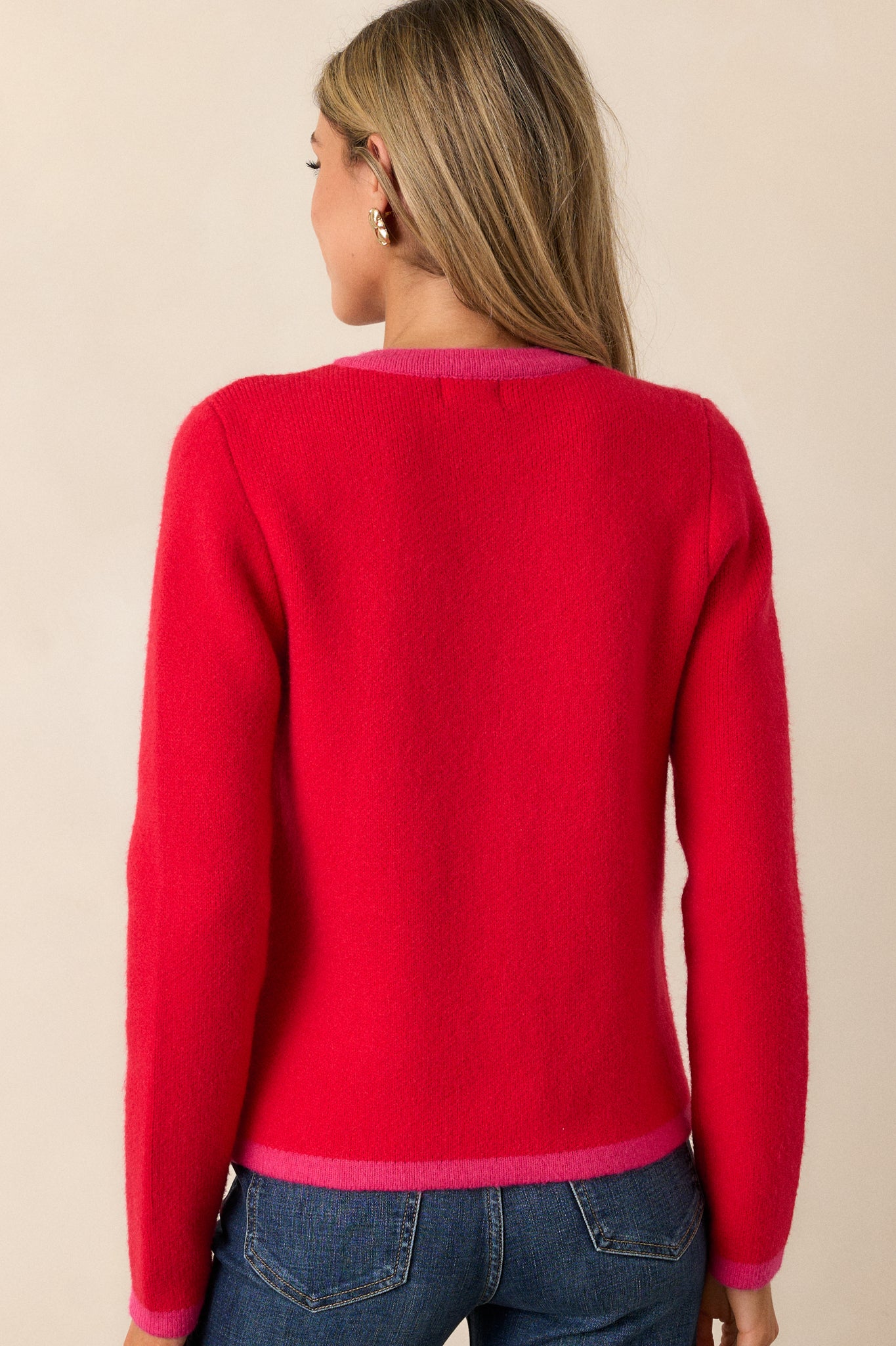 The back of the red and pink cardigan, featuring a clean, boxy fit with long sleeves and a continuous red and pink design.






