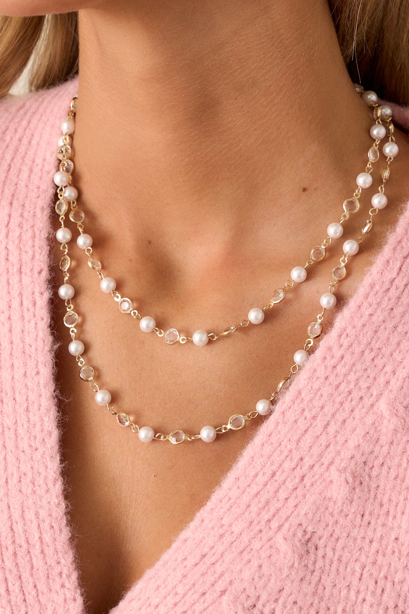 Close-up of the gold necklace, focusing on the intricate arrangement of clear rhinestones and ivory faux pearls, emphasizing the quality of the gold hardware and the overall craftsmanship.