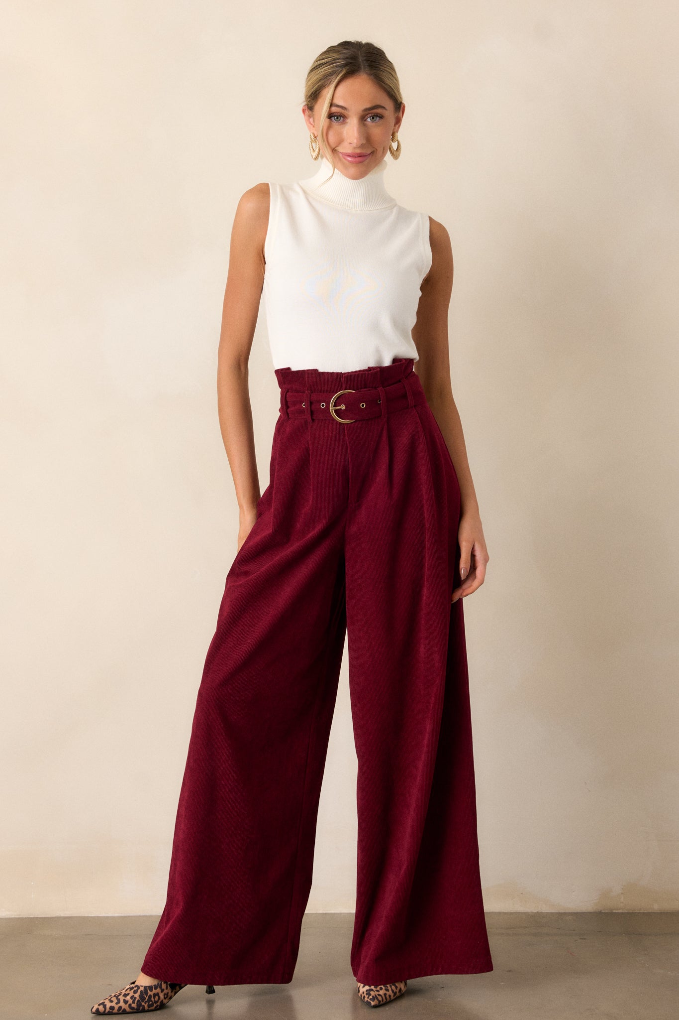 Wide-leg burgundy pants with a paper bag waist and belted detail, showcasing the loose, flowing silhouette from waist to hem.