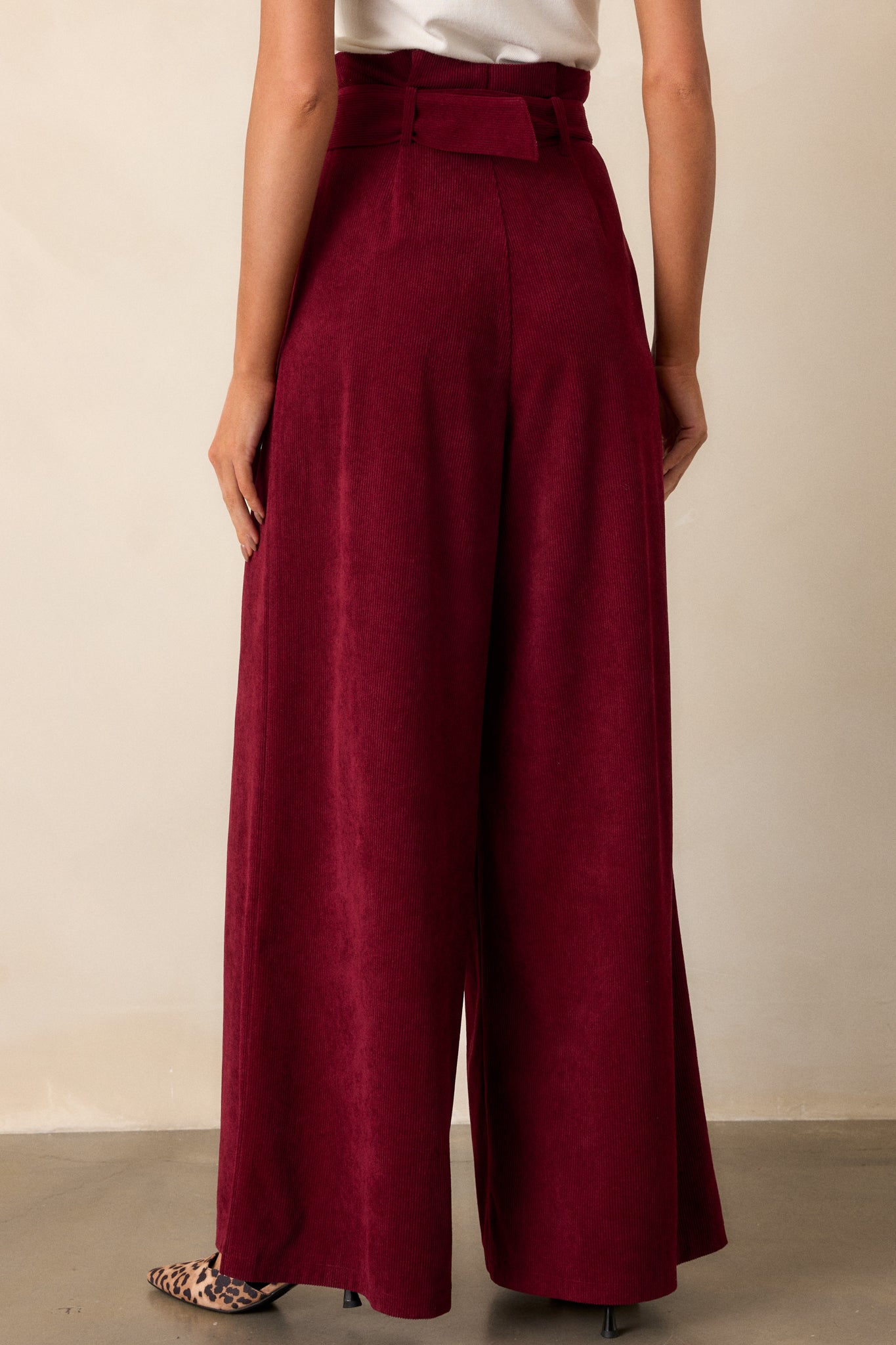 Back view of burgundy pants highlighting the paper bag waistline, the adjustable belt, and the flowy leg design.