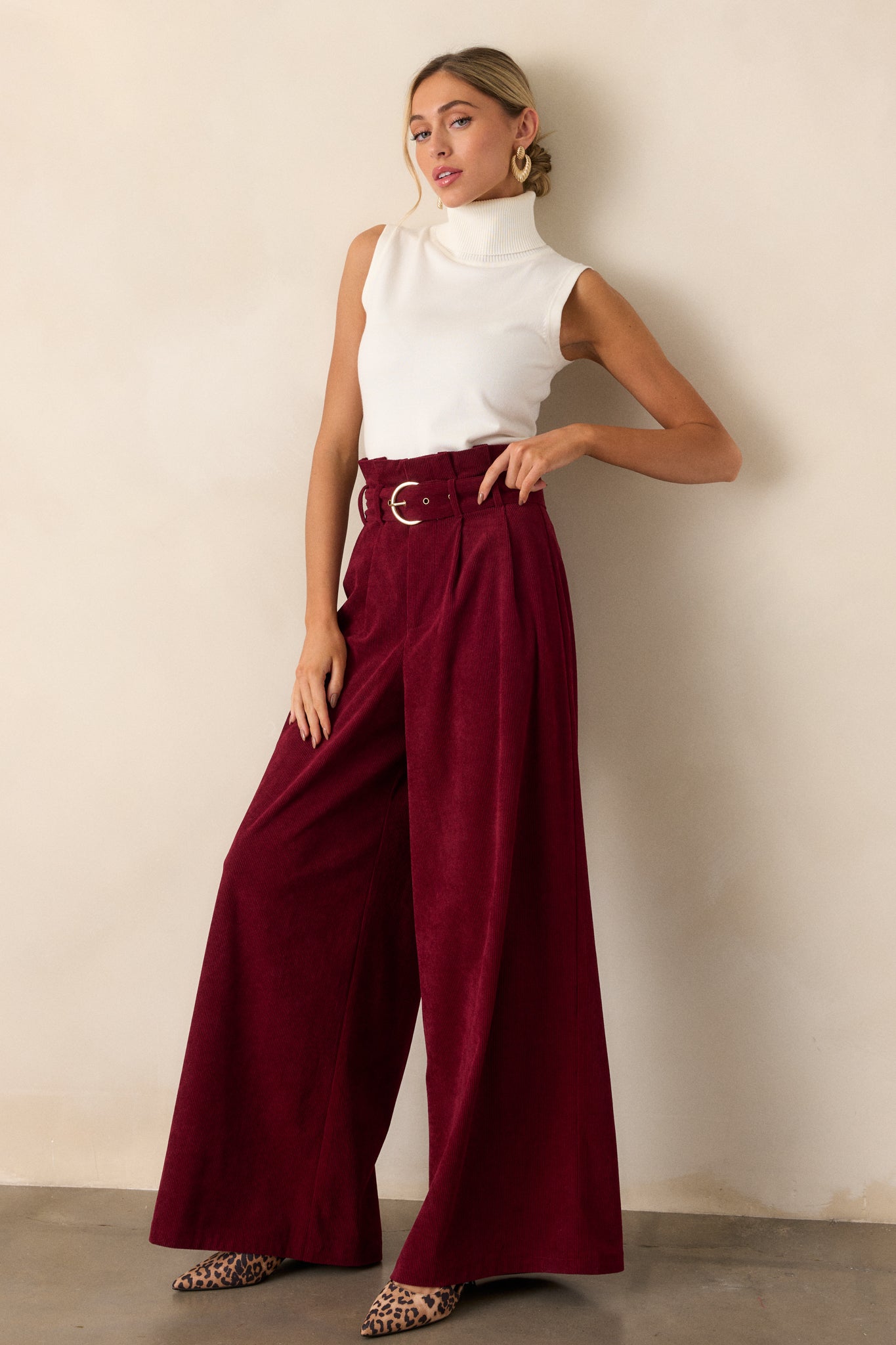 Side view of burgundy pants showcasing the paper bag waistline with the adjustable belt and the flowing leg design, emphasizing the relaxed fit.