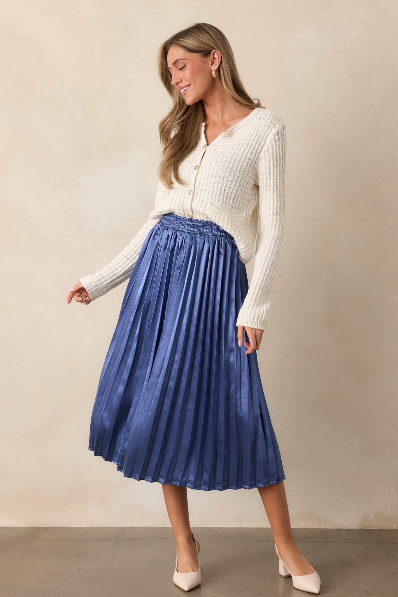 Side angle of the dusty blue skirt, highlighting the pleats and the gentle movement of the fabric as it reaches midi length.