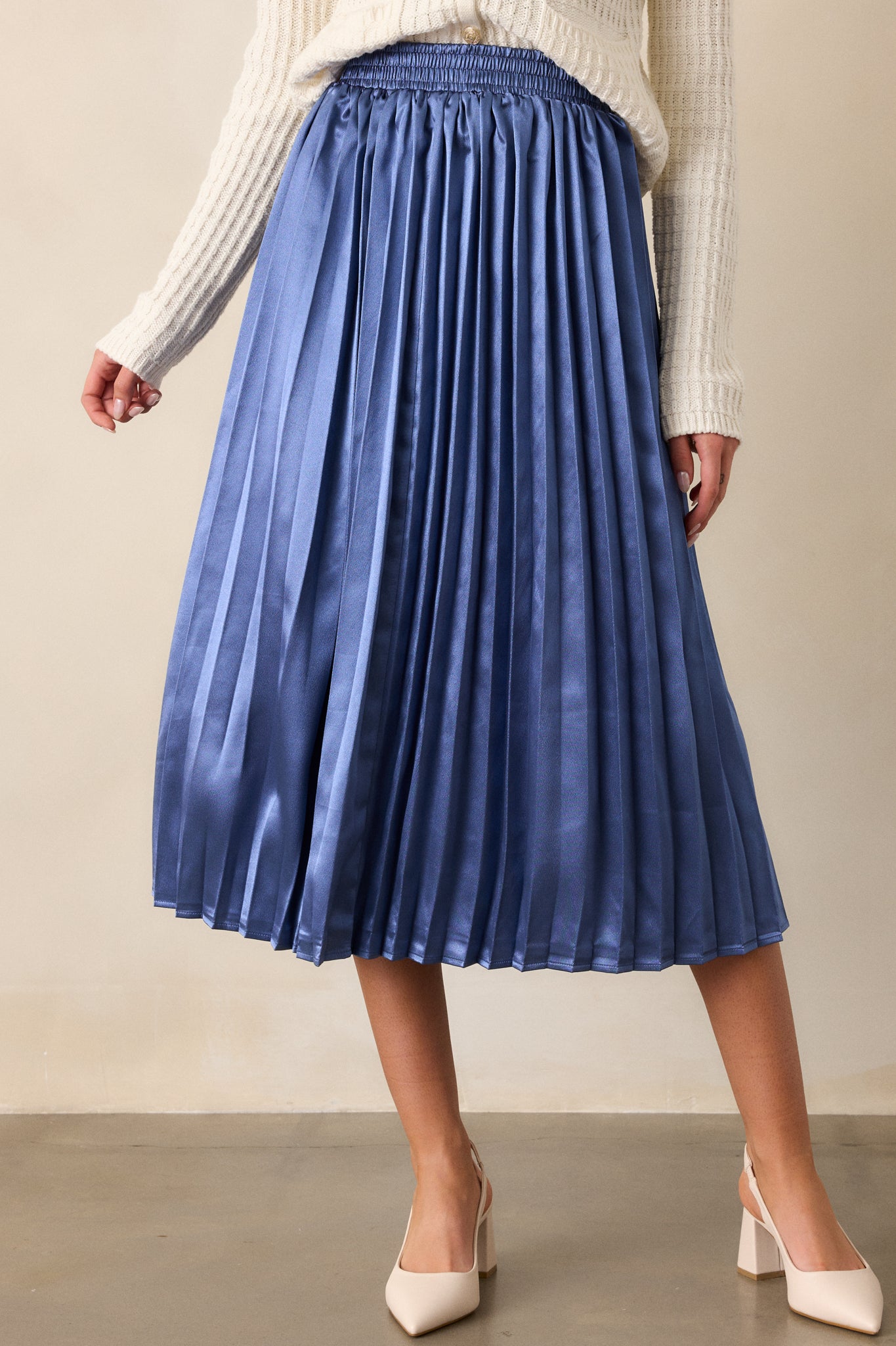 A shot highlighting the soft pleats on the dusty blue fabric, capturing the texture and gentle movement of the material.