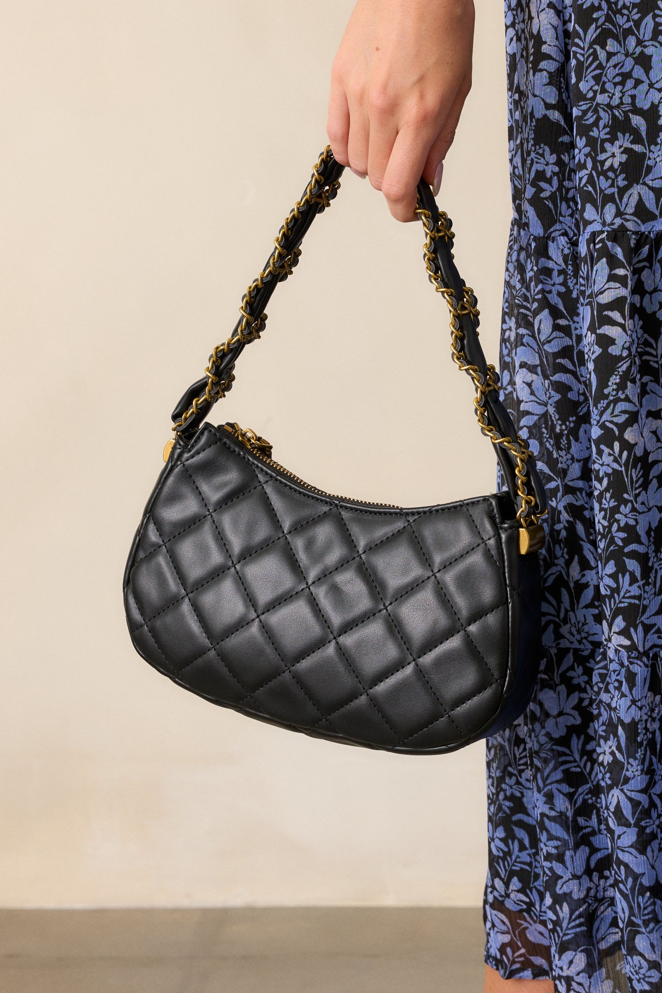 Full view of the black handbag, showcasing its quilted design, thick black and gold chain braided handle, and gold zipper closure.