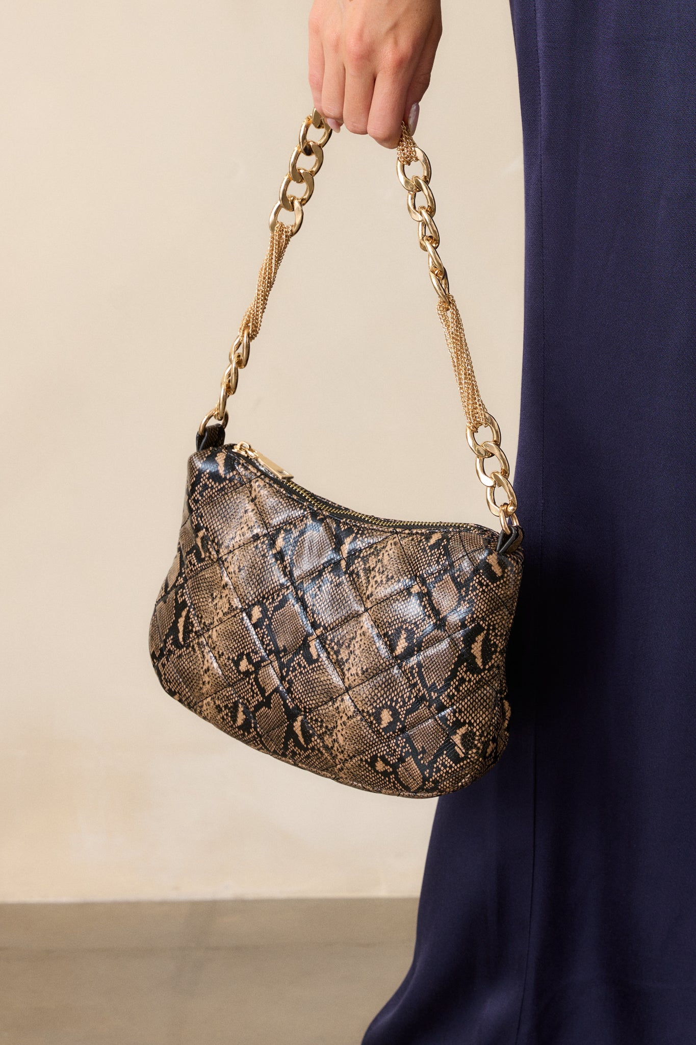 Close-up of the thick gold chain handle on the snakeskin-patterned bag, emphasizing the texture and detailing.