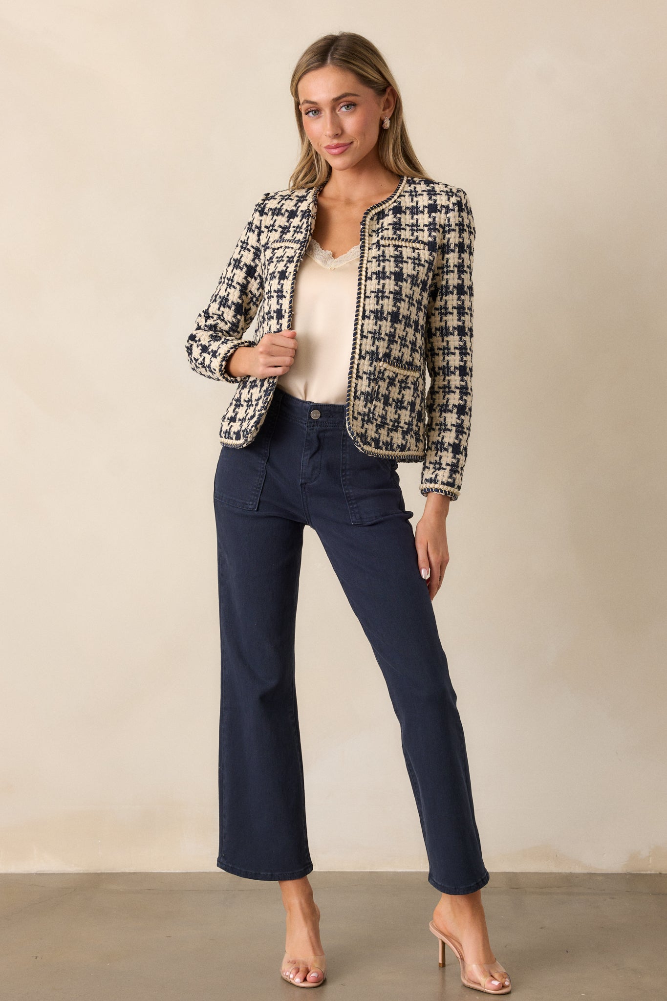 A full view of the navy tweed jacket, highlighting its structured boxy fit and elegant gold rope twist detailing across the front, with the houndstooth fabric pattern visible.