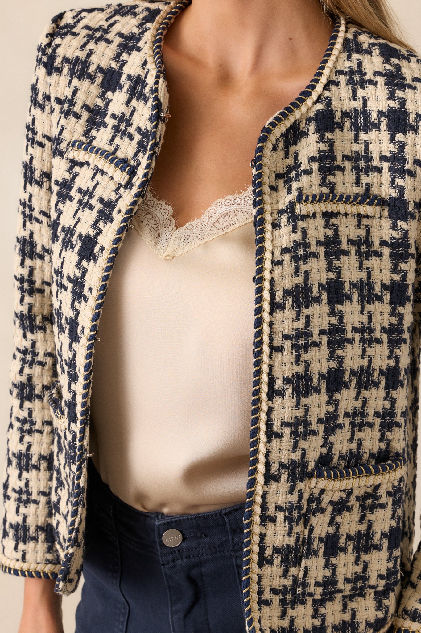 A detailed close-up of the gold rope twist trim along the front of the jacket, showing the fine craftsmanship and the houndstooth tweed texture.