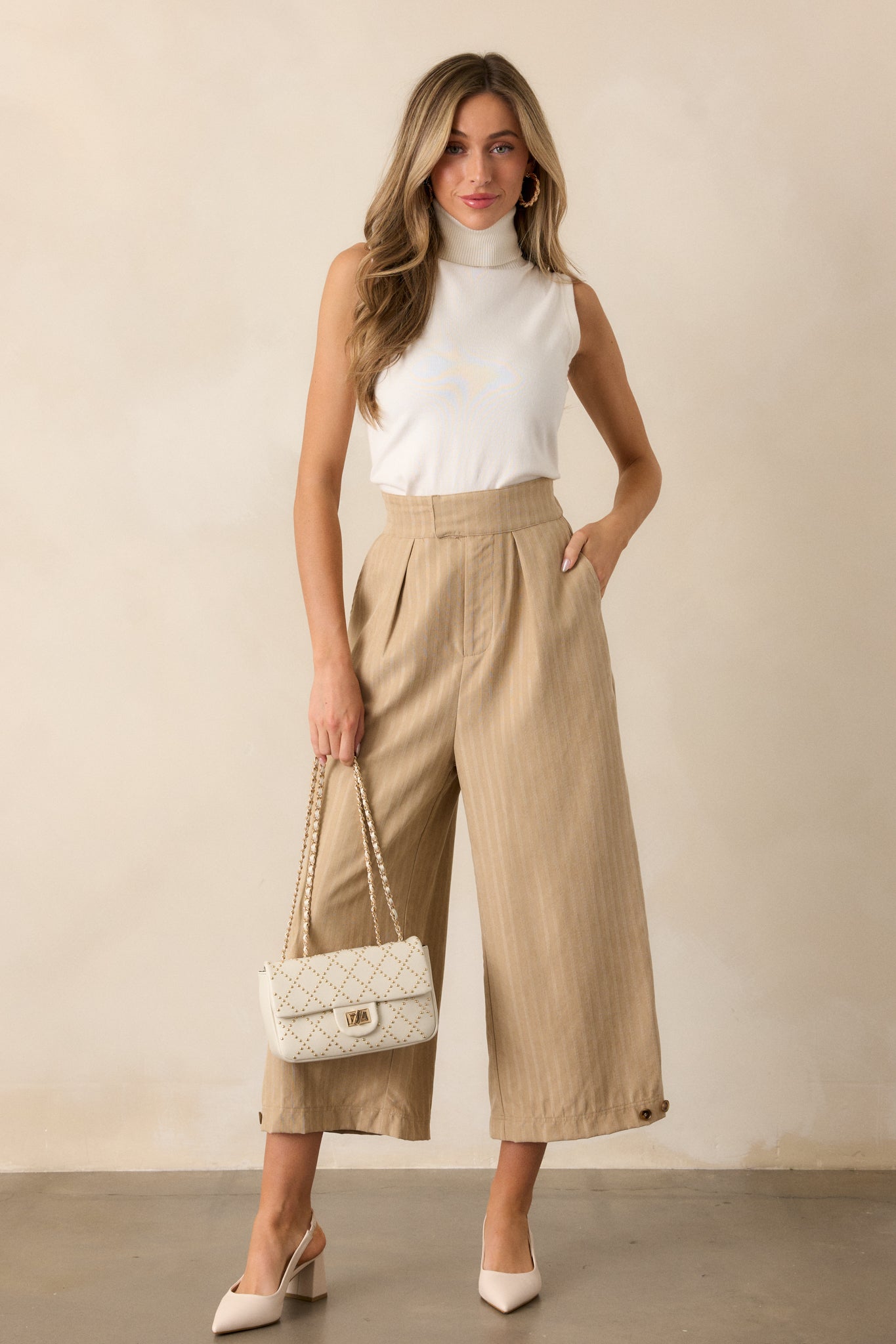 Front view of the almond pants, highlighting the high waist design, cropped length, and button cuff details at the hem.