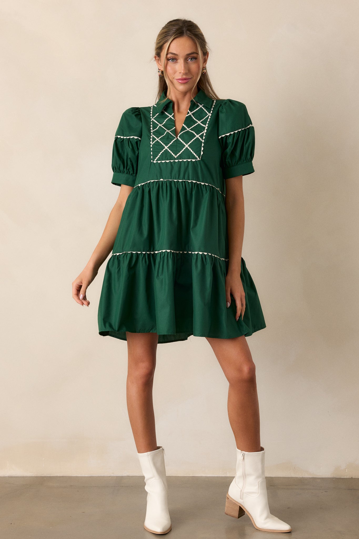 Full view of the emerald mini dress with a collared split neckline, tiered design, and white cross stitch yoke detailing.