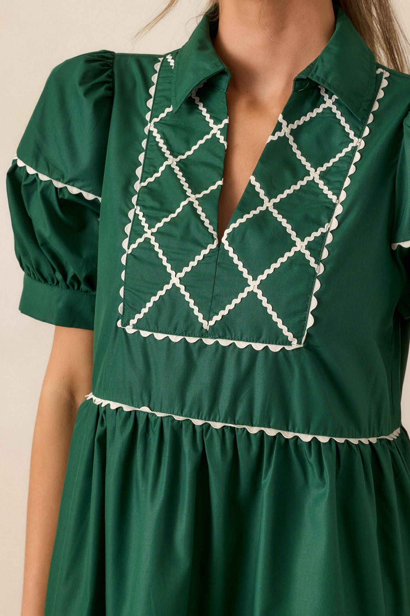 Close-up of the cross stitch yoke detailing in white on the emerald mini dress, showcasing the fine embroidery.