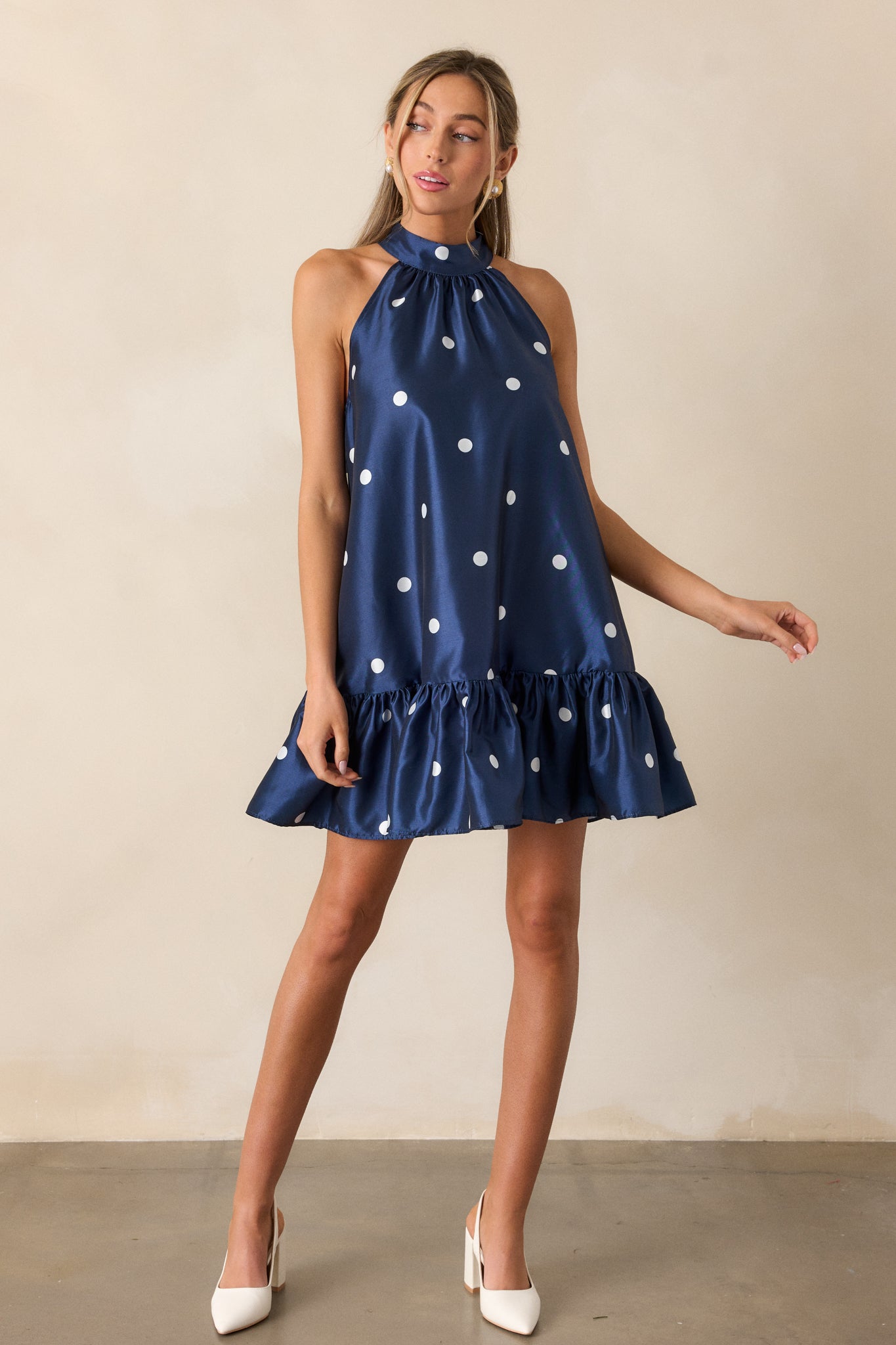 A full length image of the dress, emphasizing its babydoll silhouette and the playful polka dot design. The ruffled bottom hem adds a feminine touch to the dress, and the halter neckline is accentuated.