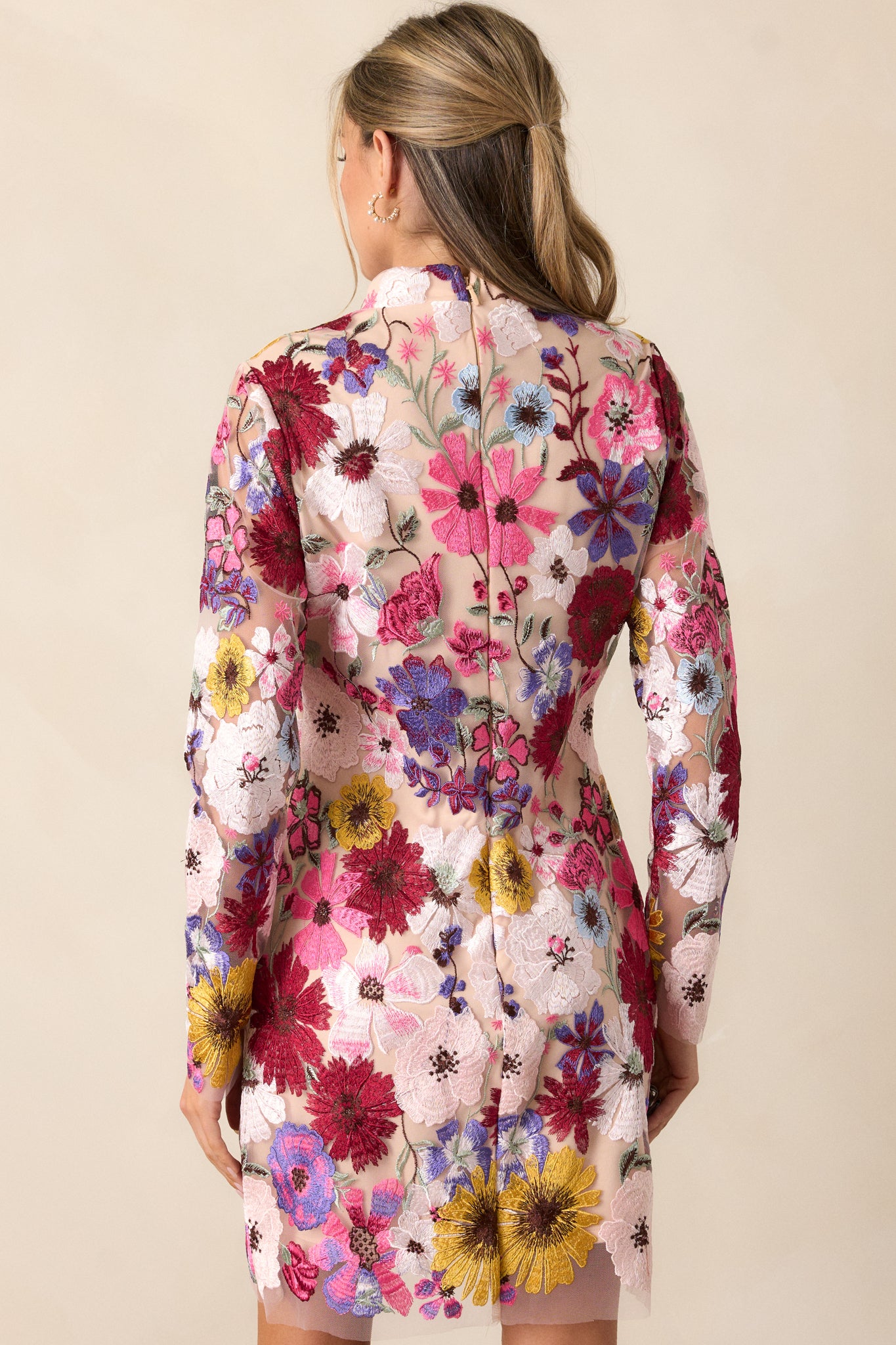 Back view of the dress, showing the discrete back zipper and the flow of the sheer floral overlay, along with the sheer long sleeves.