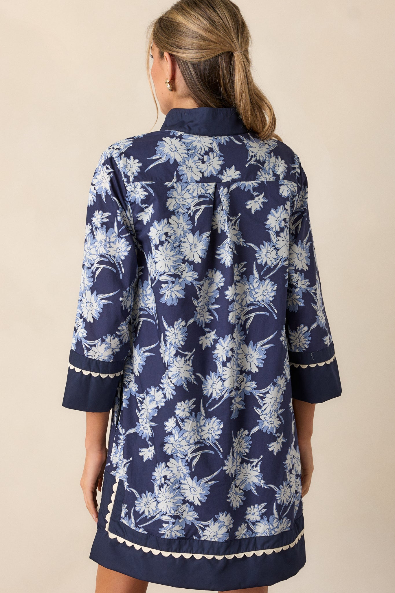 Back view of the navy dress, showing the clean design with long sleeves and a subtle floral pattern across the back, with a smooth fit.