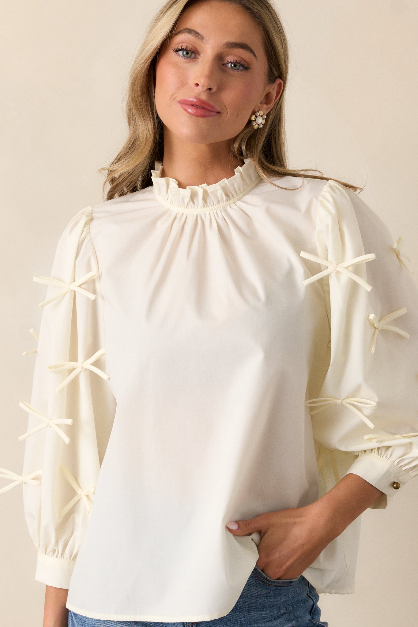 Close-up of the high ruffle neckline on the ivory blouse, showing the delicate keyhole detail with a button at the back.