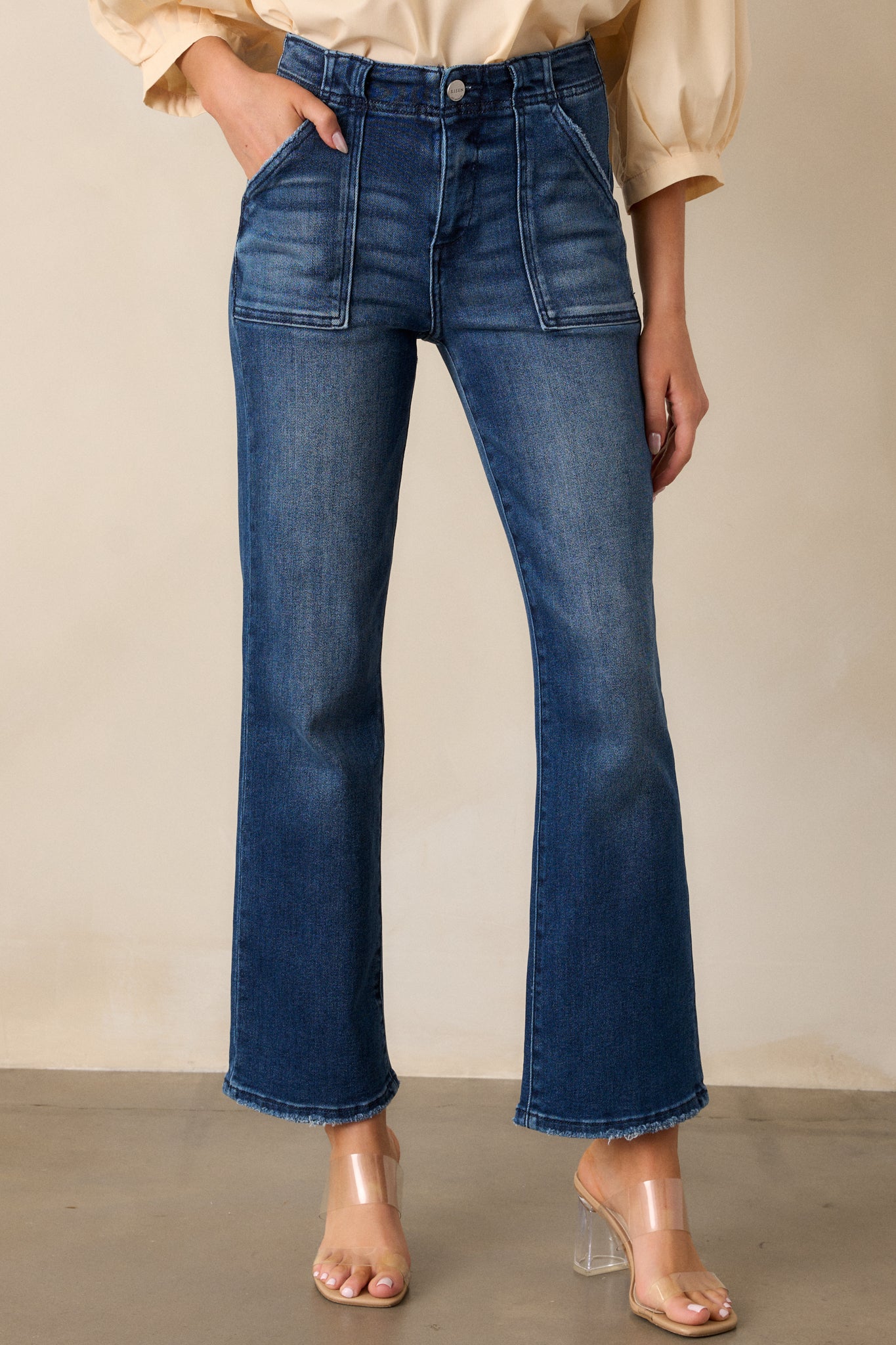 Close-up of the front of the jeans, focusing on the high waisted fit, large front pockets, and the button and zipper closure detail.