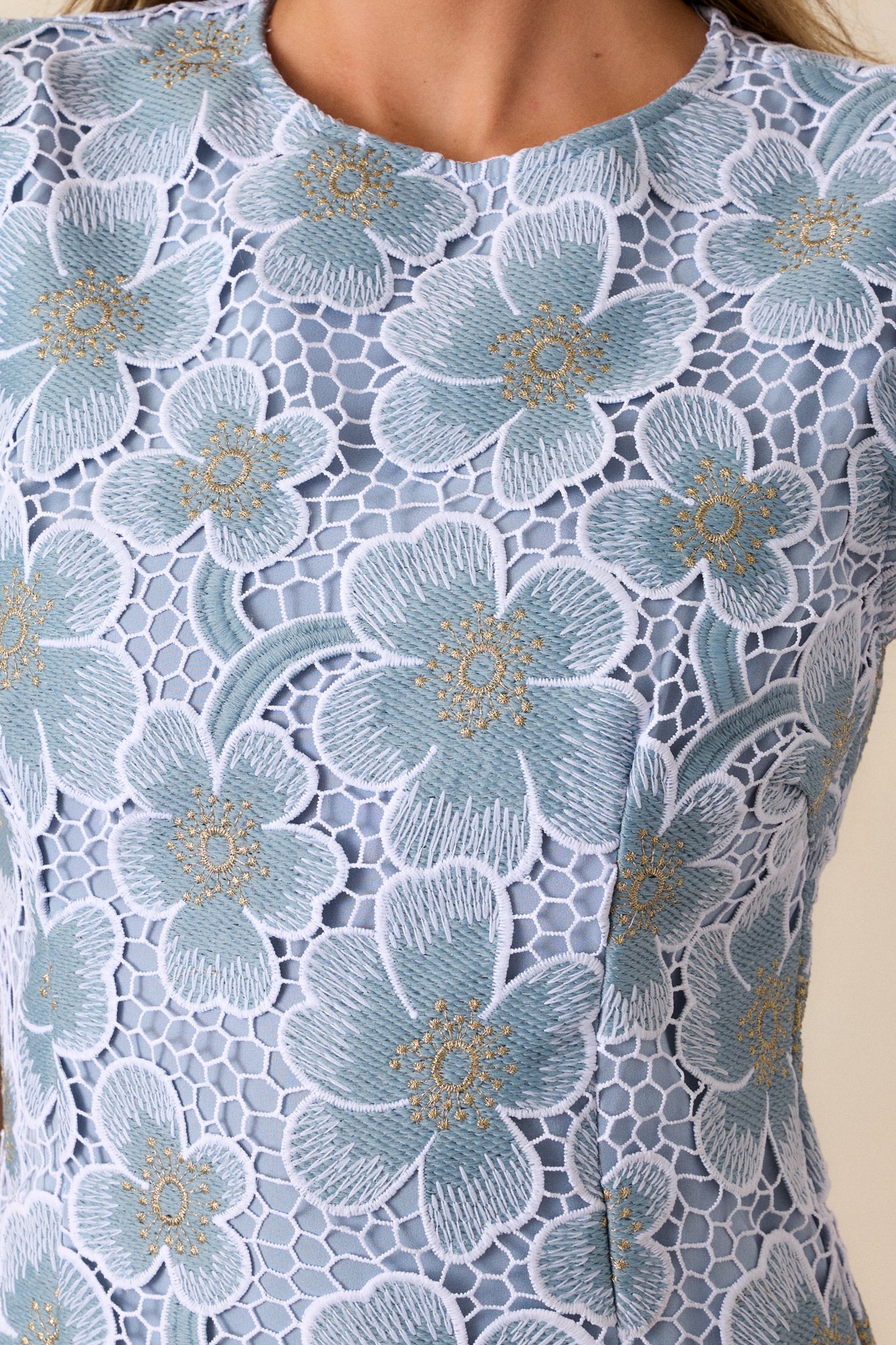 Detailed shot of the floral embroidery on the sky blue fabric, showing the texture and intricate stitching of the floral designs.