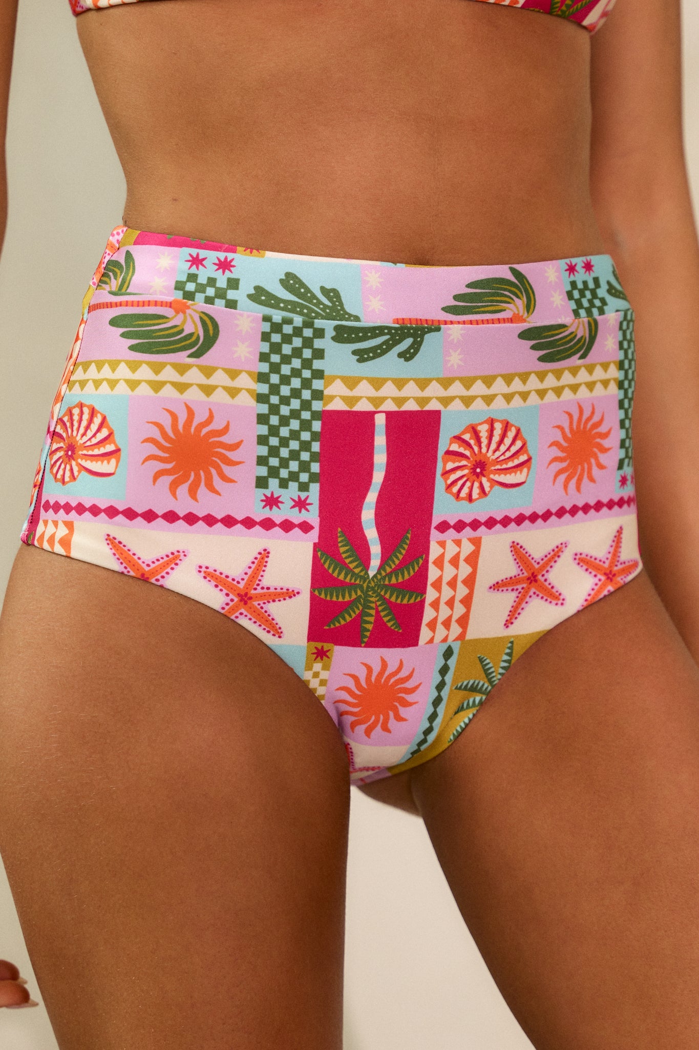 Close-up of the high-waisted design of the pink bikini bottoms, highlighting the tropical pattern.