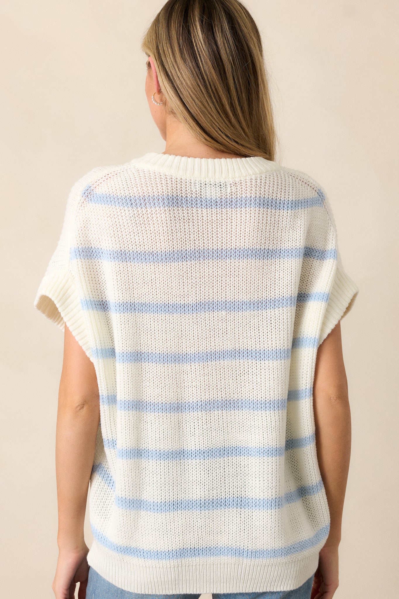 A back view of the white sweater top, showing the relaxed fit and short oversized sleeves. The striped pattern continues across the back, and the ribbed bottom hem is visible at the waist.