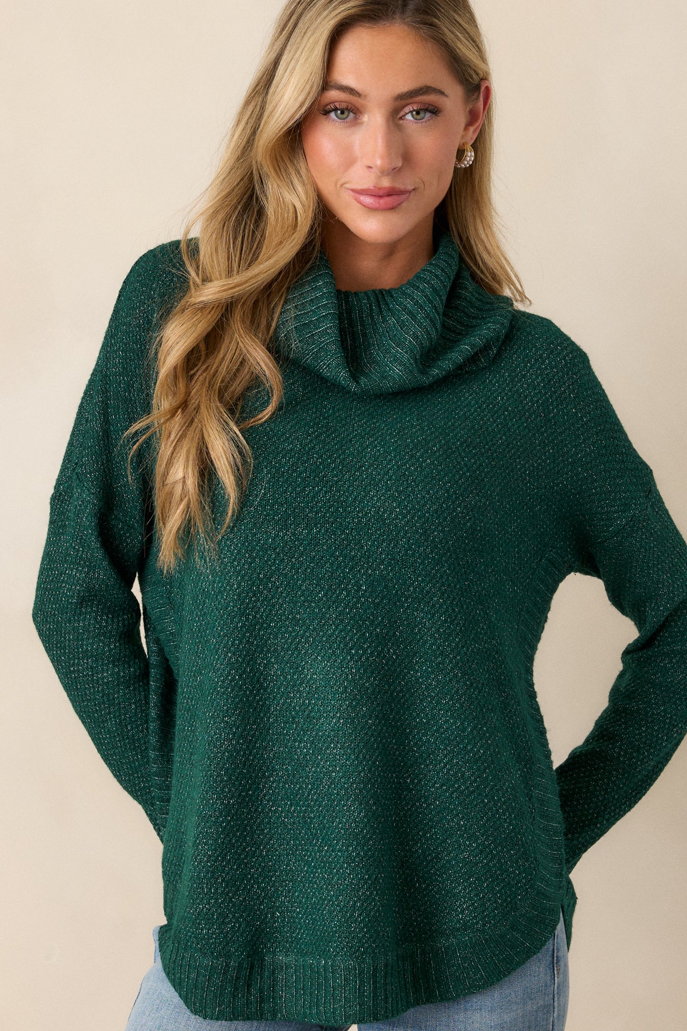 Zoomed-in shot highlighting the soft drape of the cowl turtleneck and textured speckles on the green sweater.