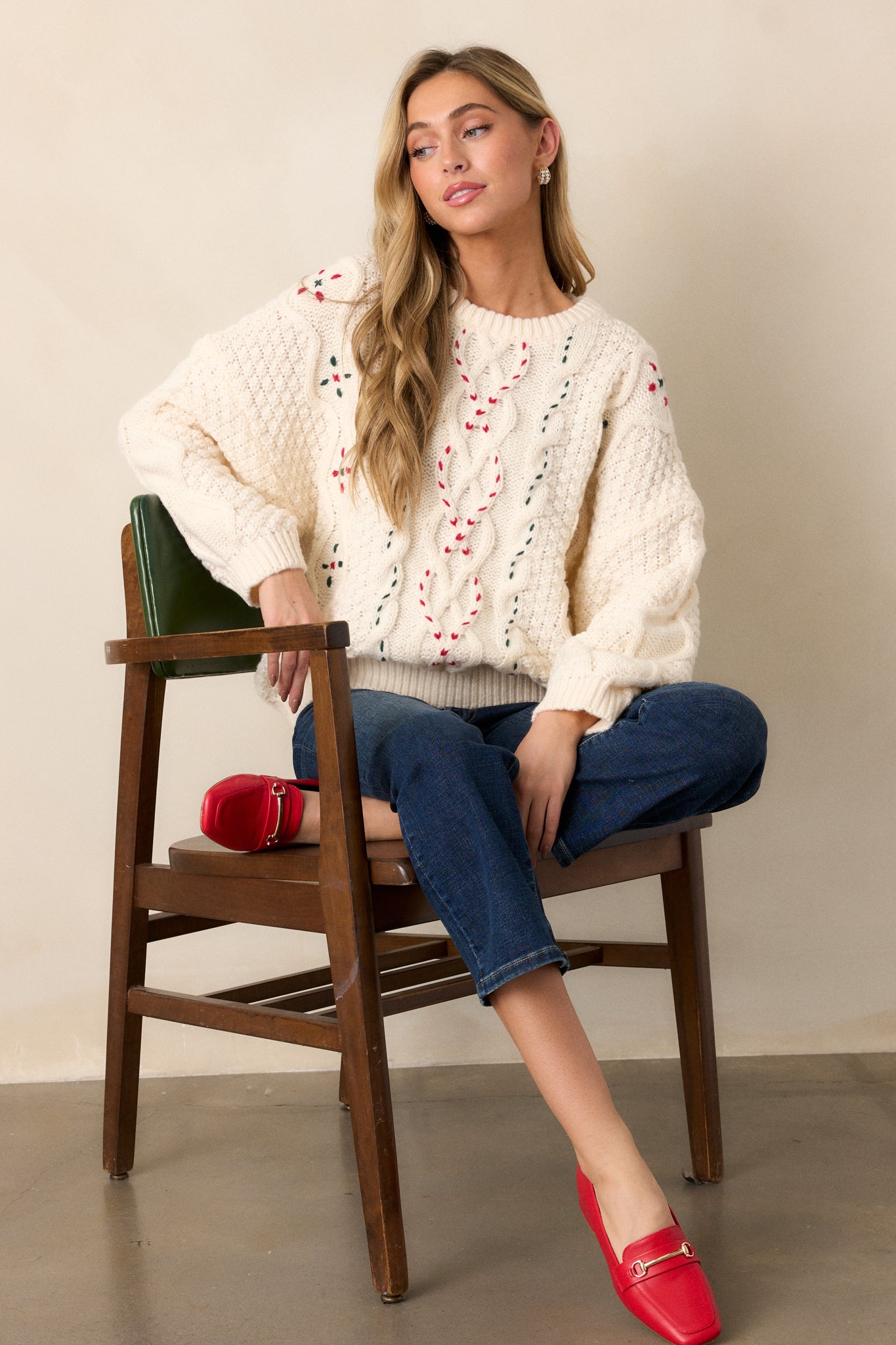 Ivory sweater top with a round neckline, featuring various cable knit designs, red and green thread accents, and an oversized fit with long sleeves.