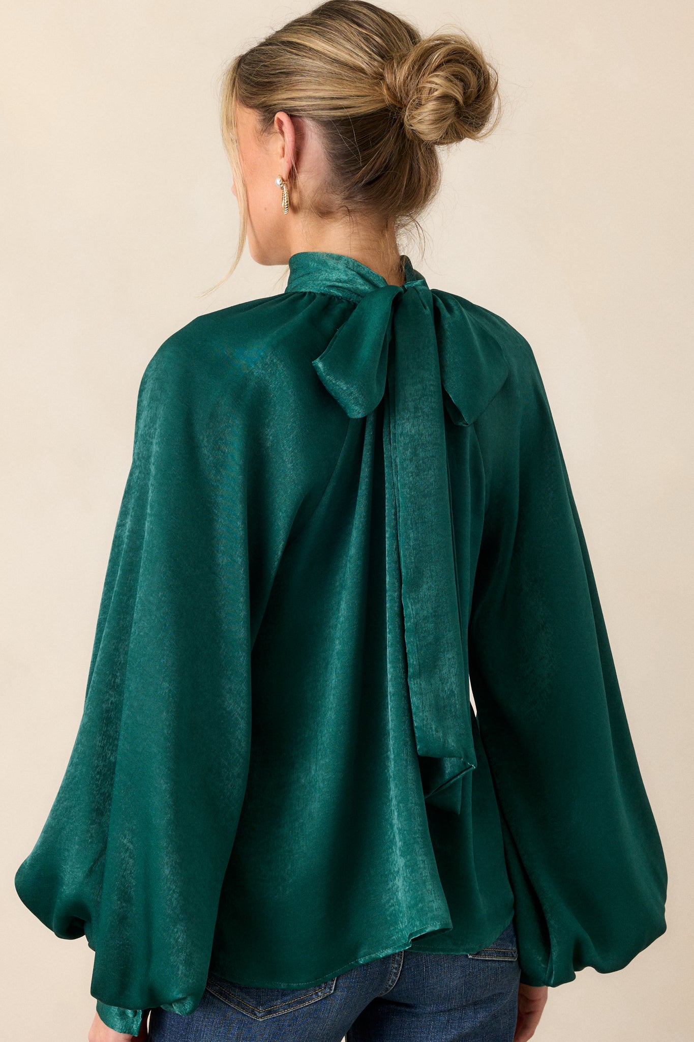 A view of the back of the top with the self-tie styled as a bow at the back, highlighting the flowy fit and smooth fabric from behind.