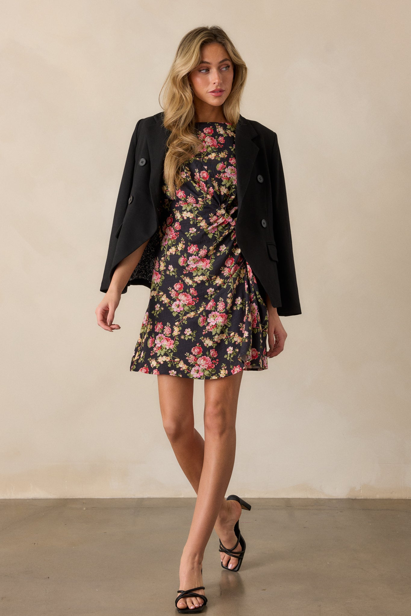 Full view of a black midi dress with a high neckline, floral design, cap sleeves, and side twist detailing.