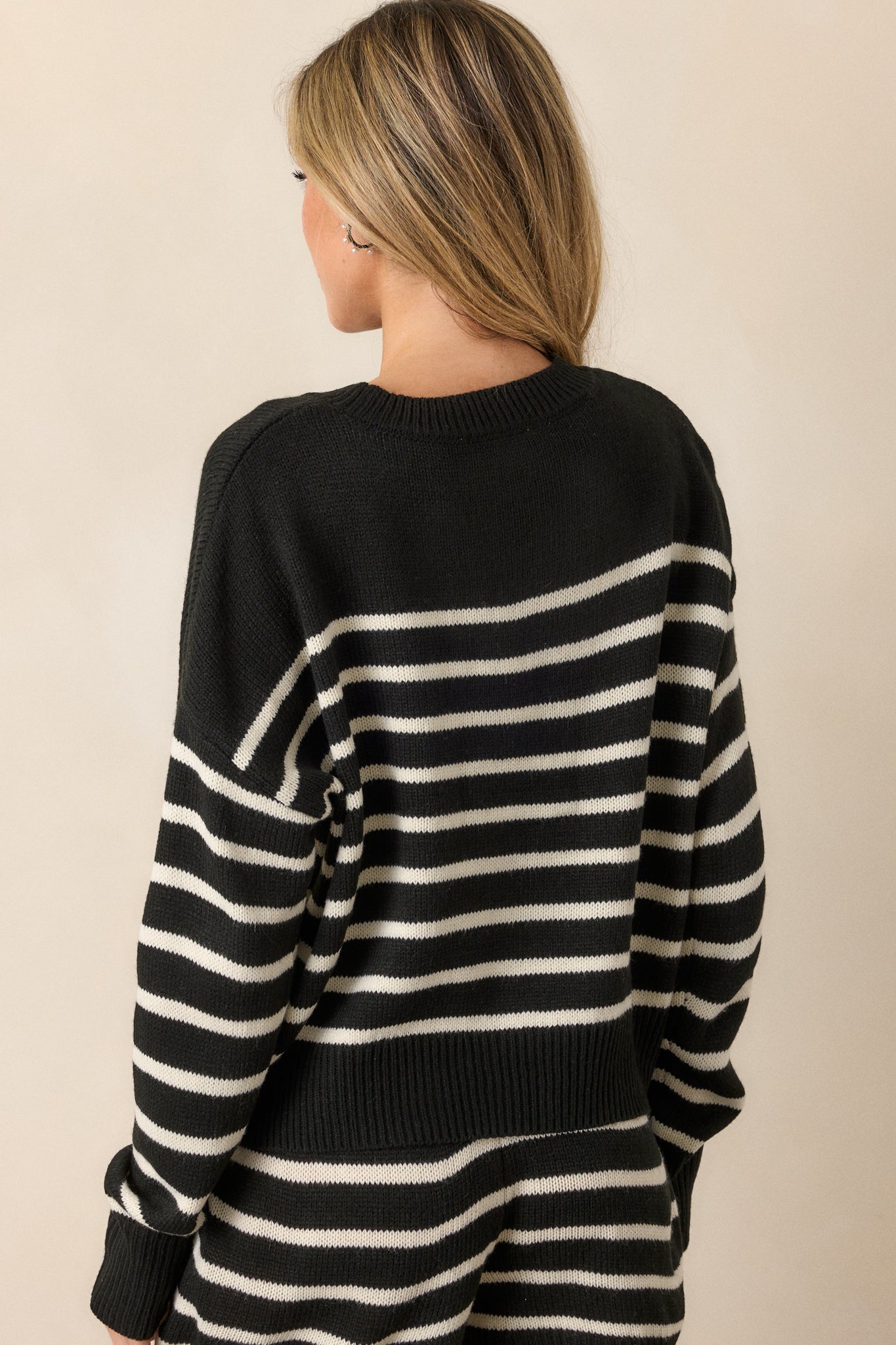 View of the back of the sweater, featuring the continuous horizontal stripe design and the clean ribbed hem for a polished look.