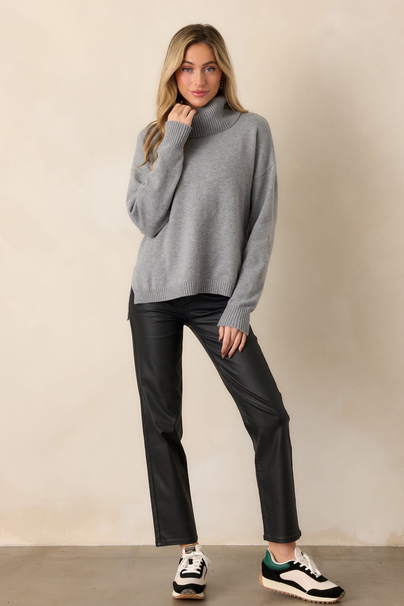 Full body view of a grey sweater featuring a chunky cowl neckline accompanied by ribbed detailing, straight long sleeves completed by ribbed cuffs, and a straight hemline.