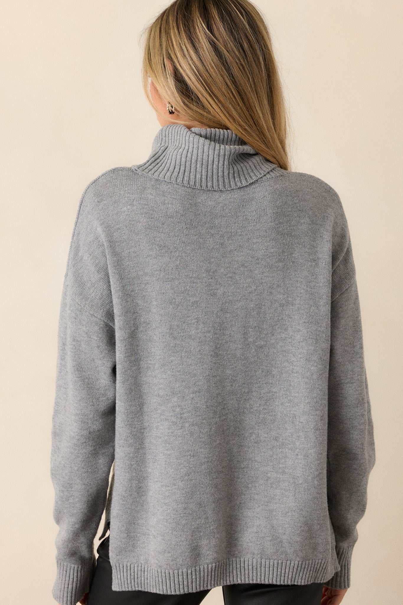 Back view of a grey sweater featuring a chunky cowl neckline accompanied by ribbed detailing, straight long sleeves completed by ribbed cuffs, and a straight hemline.