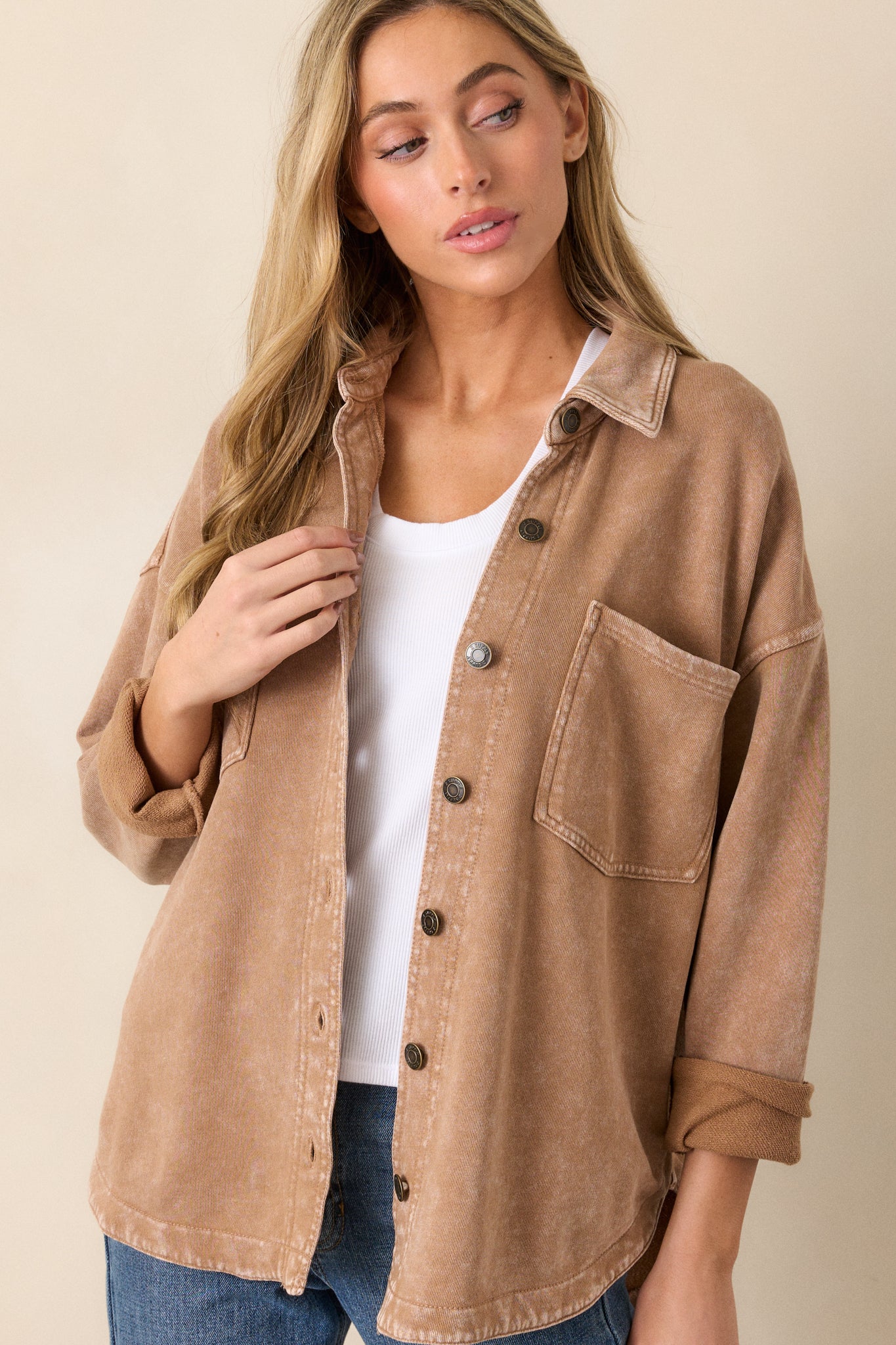 This jacket features a collared neckline, dropped shoulders, functional chest pockets, and a full button front