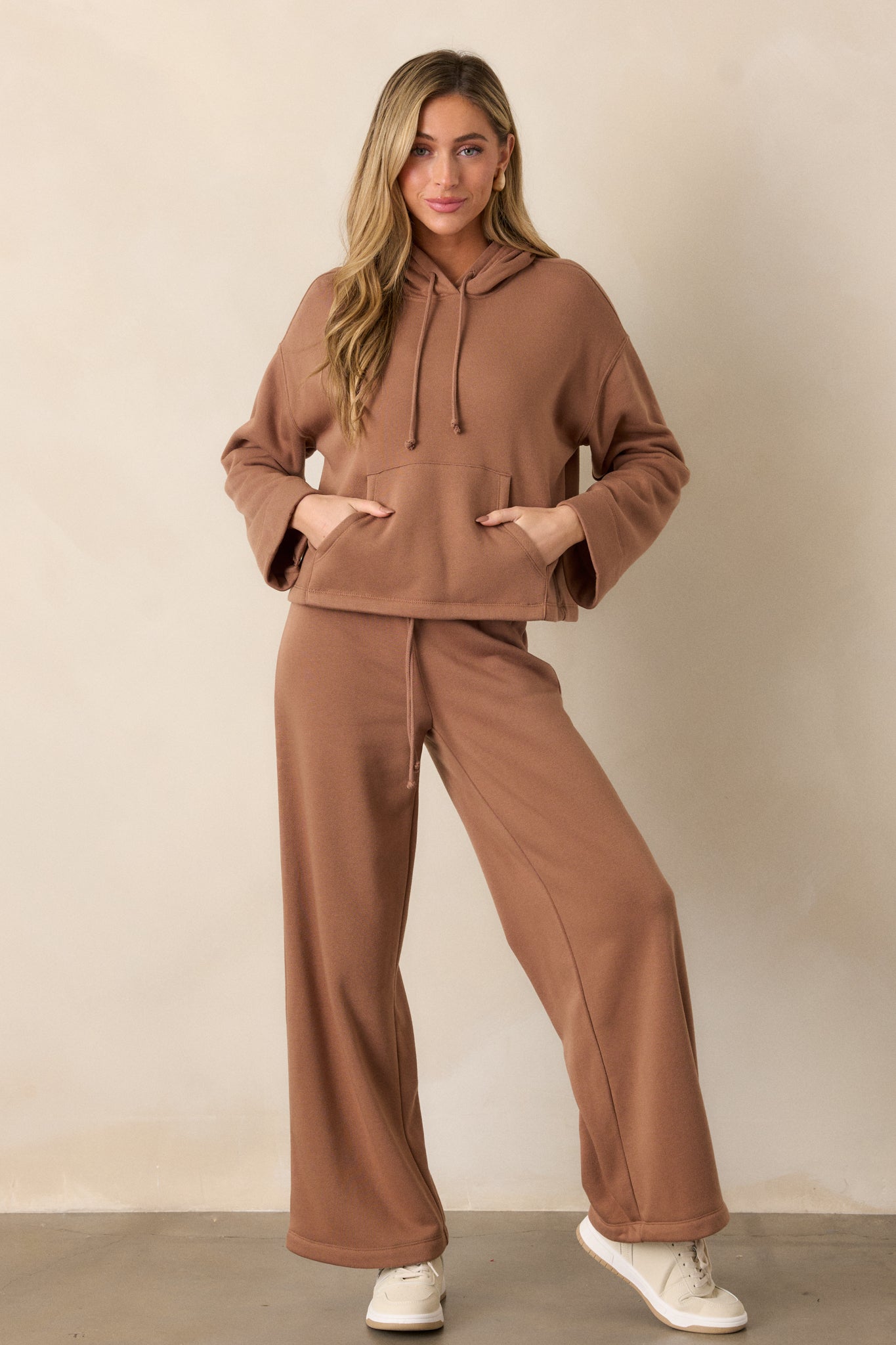 Full-length shot of the brown sweatshirt, showing the relaxed fit, hood with drawstring, and front kangaroo pocket.