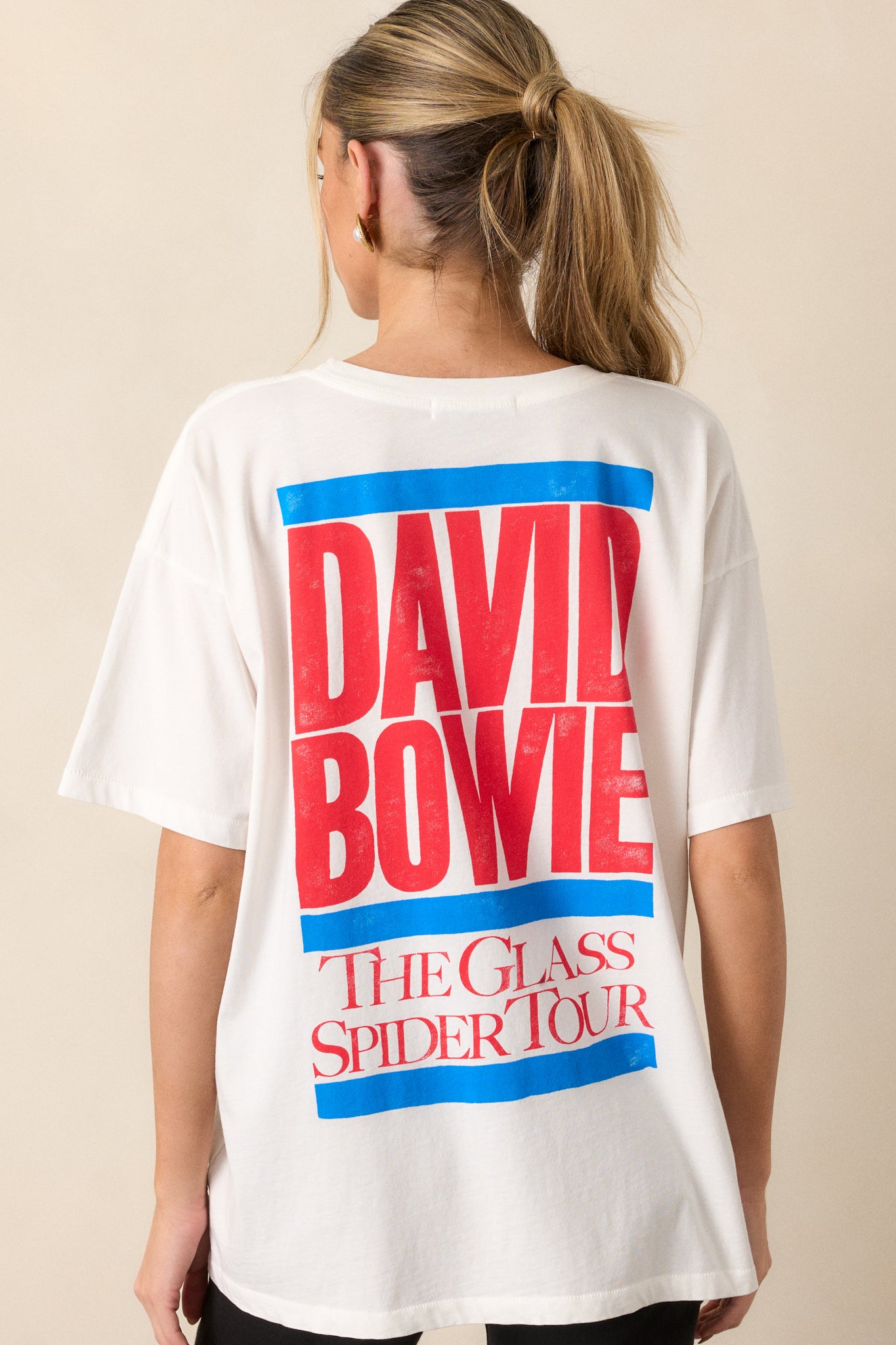 A view of the back of the tee, showcasing the "David Bowie The Glass Spider Tour" graphic on the back, along with the simple white fabric and round collar.