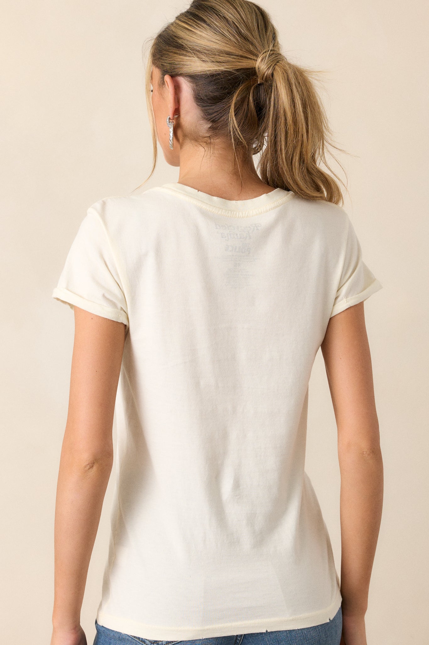 A back view of the ivory tee, showing the simple, clean design with no graphic, highlighting the relaxed fit and cuffed sleeve details.