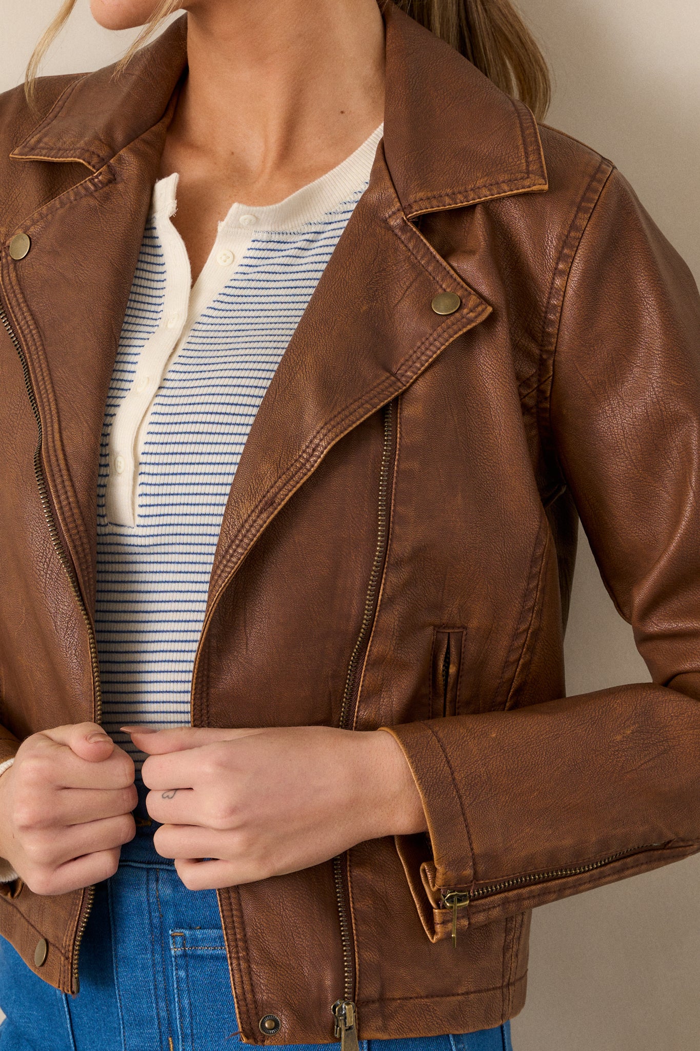 Close-up of the jacket showing the washed gold hardware, collar neckline with snap buttons, front functional zipper, and one of the three functional zipper pockets.