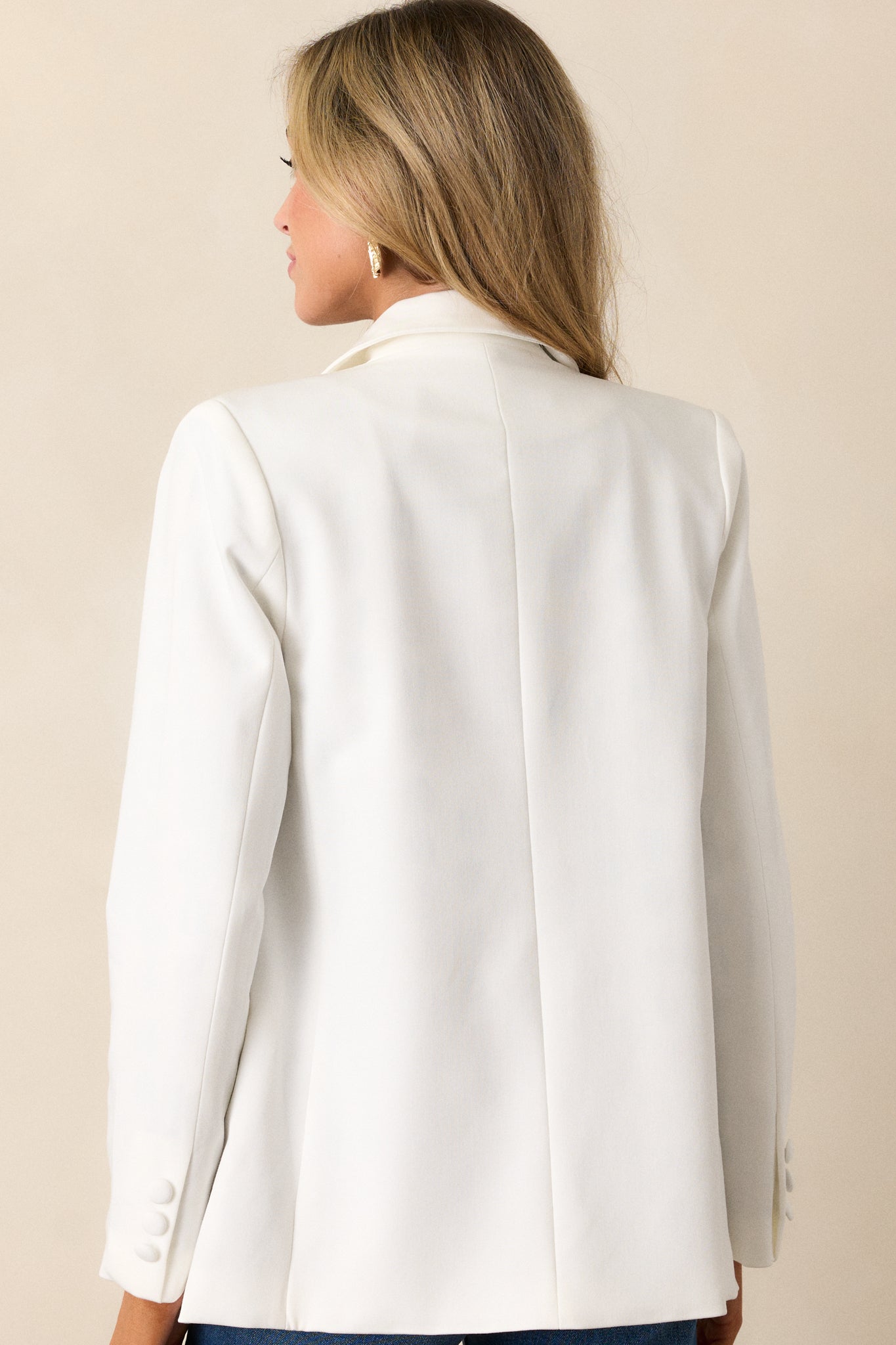 Back view of this white blazer that  features two functional pockets, functional buttons, a lapel collar, lightweight shoulder pads, and a multicolor print lining.