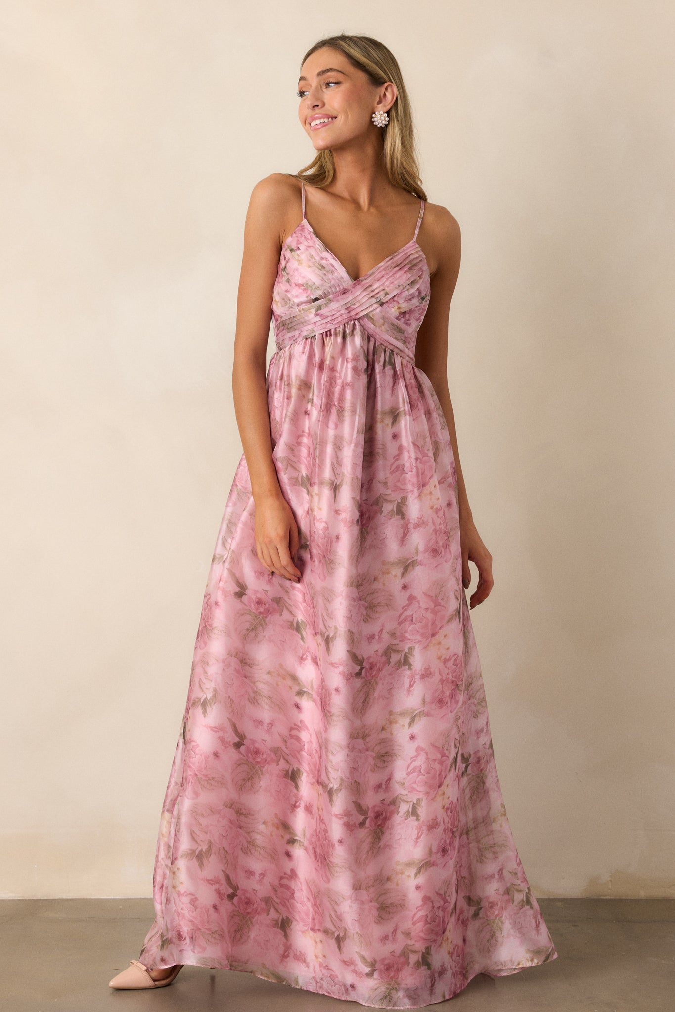 A pink floral maxi dress with spaghetti straps, a cross pleated bust, a v-neckline, and empire waist.