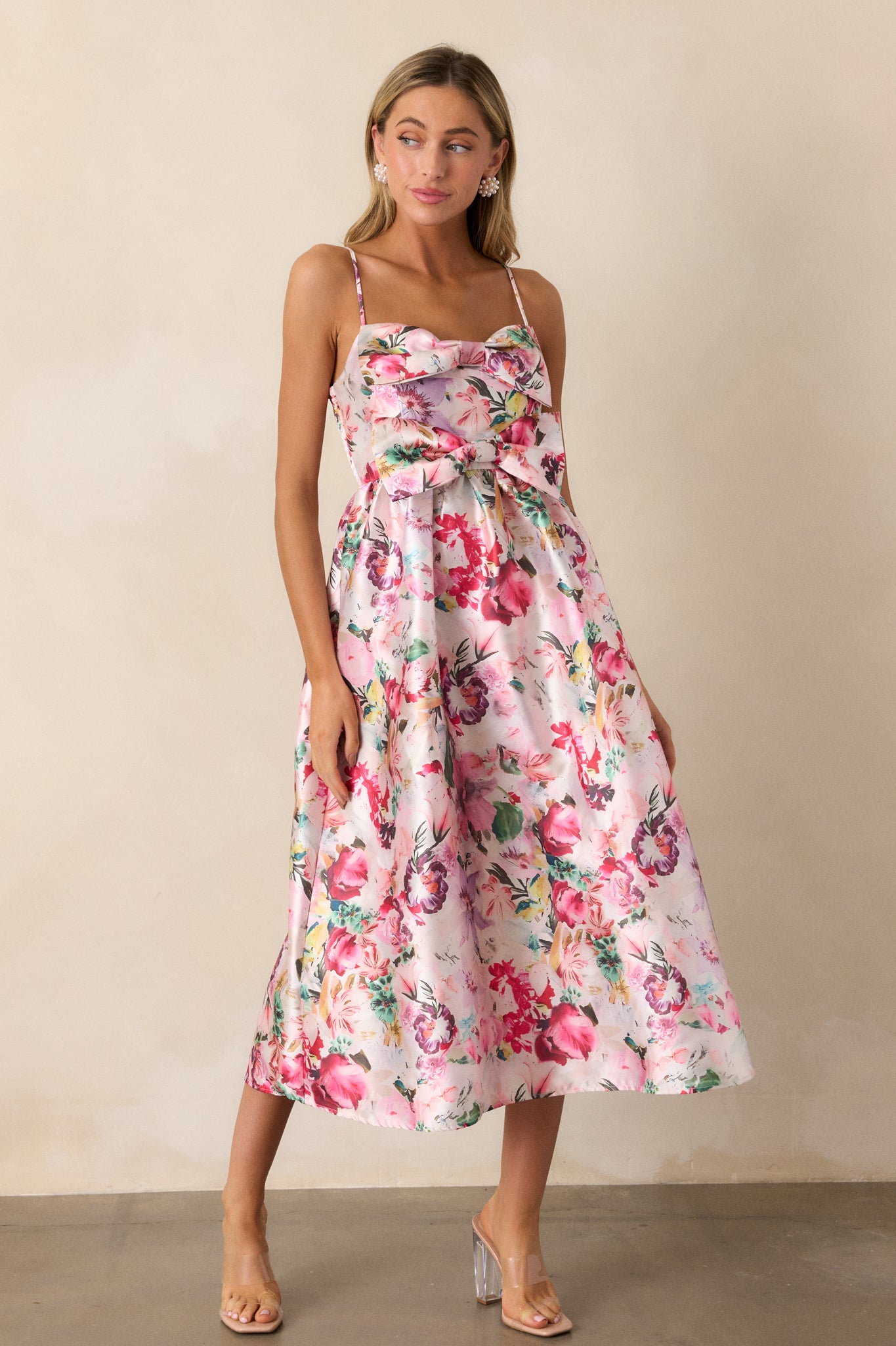 A full view of the pink dress, showcasing the slight v-neckline, sleeveless design, and fit-and-flare silhouette with colorful floral print.