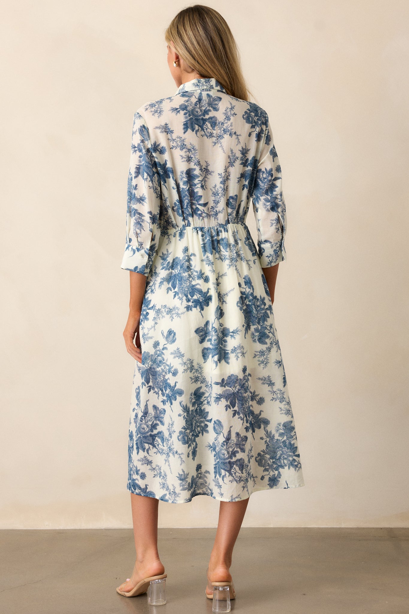 View of the back of the dress, featuring the collared neckline, continuous floral pattern, and the smooth fall of the fabric down to the midi length.