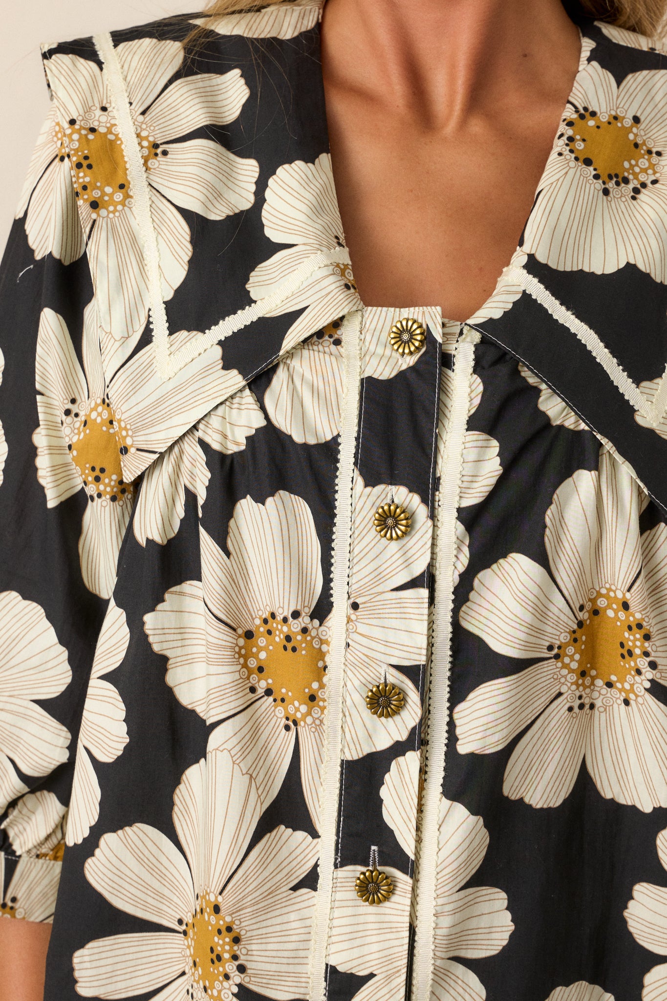 A detailed shot of the worn gold flower buttons and ivory floral pattern, capturing the texture and intricate design.