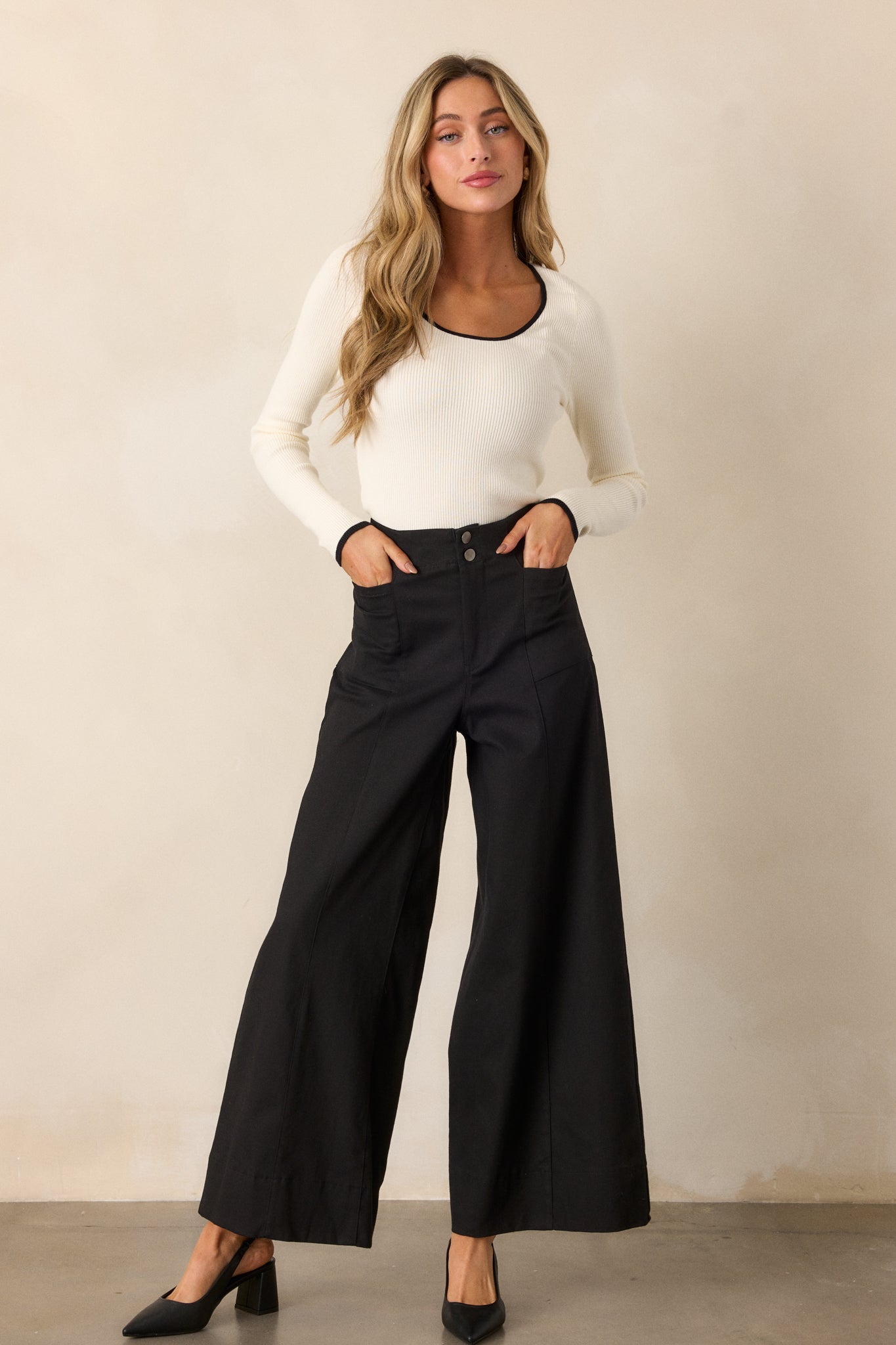 These black pants feature a high waisted design, a button zipper closure, functional rectangular hip pockets and a wide leg.