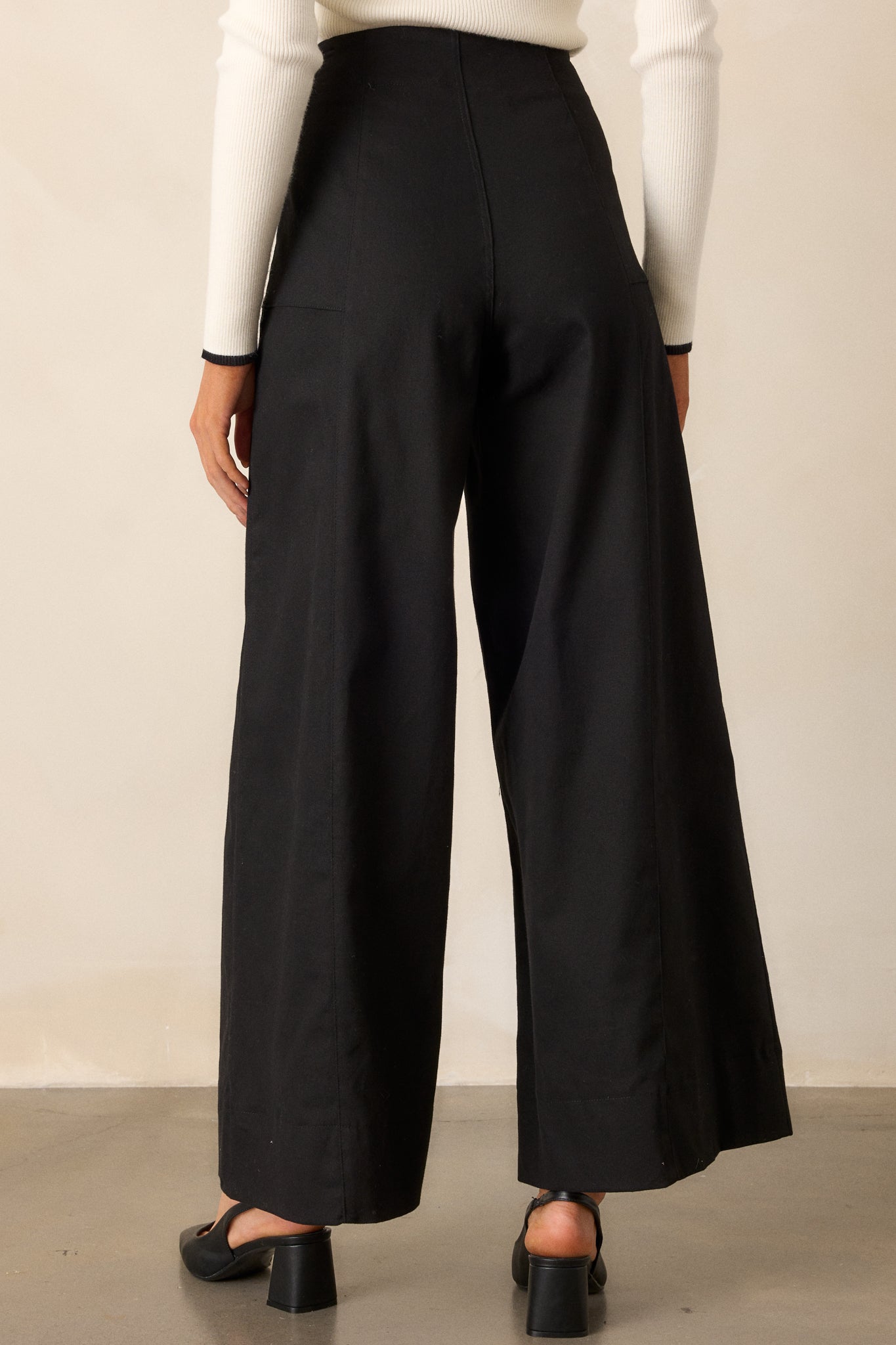 Back view of black pants highlighting the high waisted design and the wide leg cut.