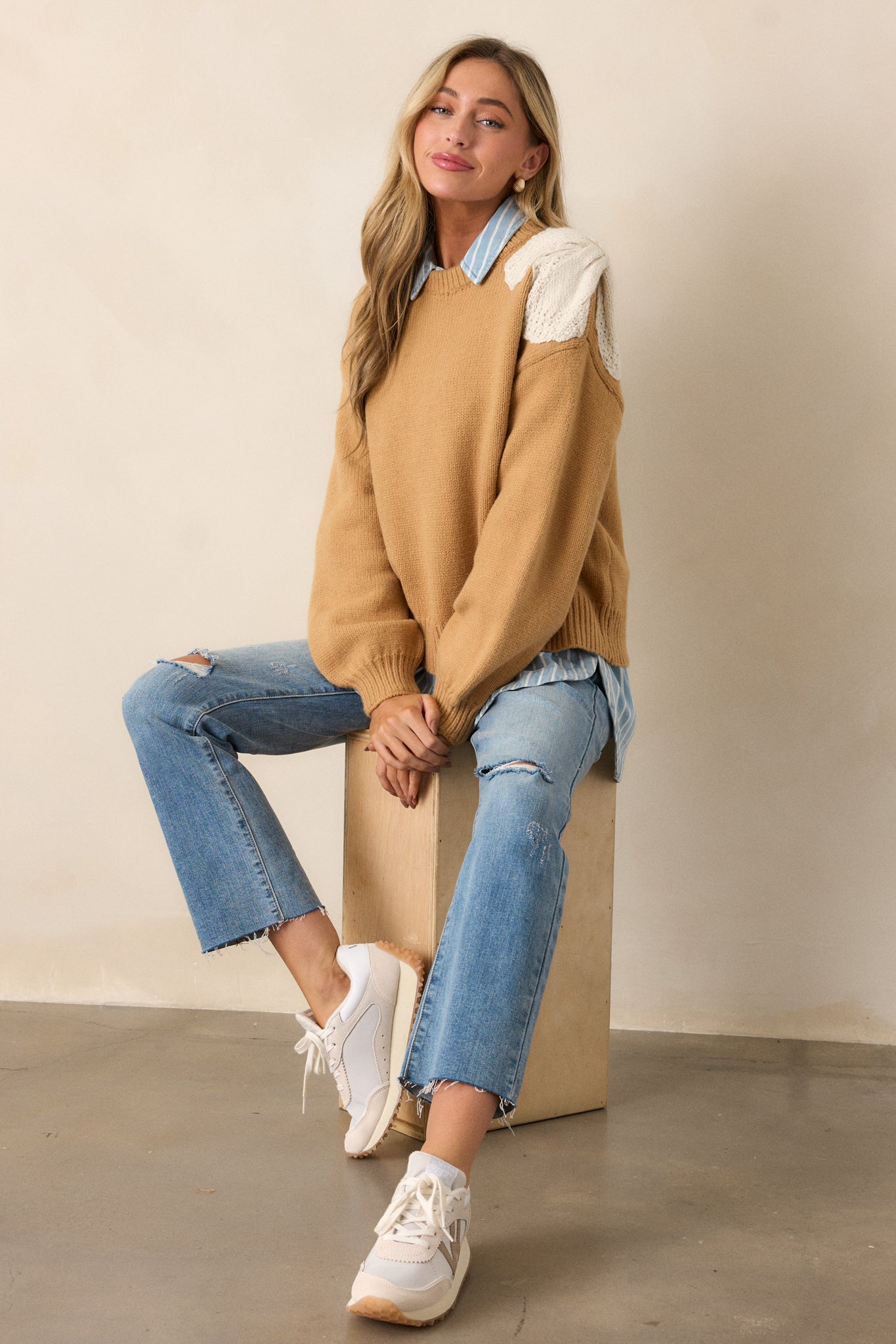 A full view of the honey-colored sweater, showcasing the ribbed rounded neckline, boxy fit, and long sleeves with ribbed knit cuffs.