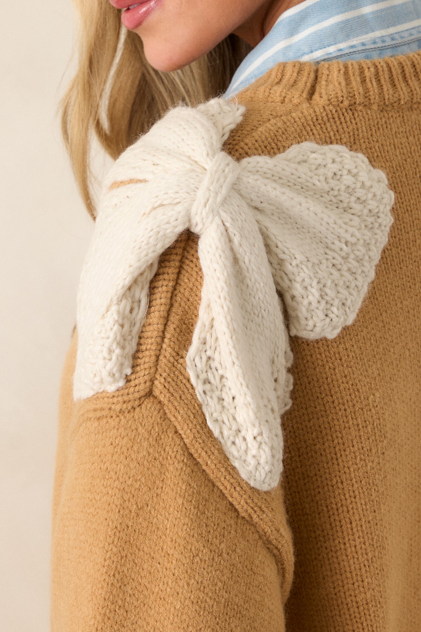 A zoomed-in shot of the crocheted ivory bow detailing on the shoulder, highlighting the intricate design and contrast with the honey fabric.